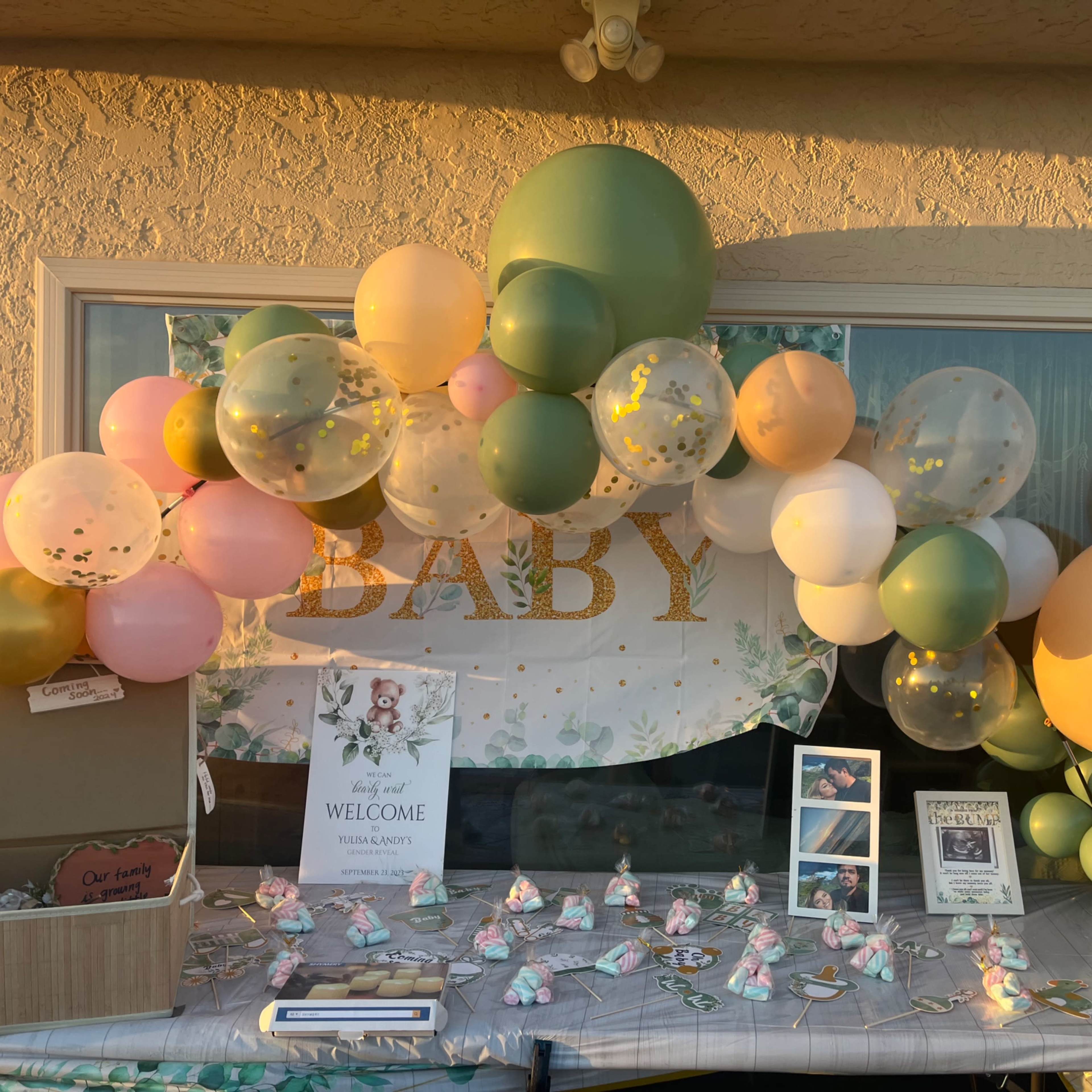 A decorative arch made of colorful balloons frames a welcome sign at a baby shower setup.