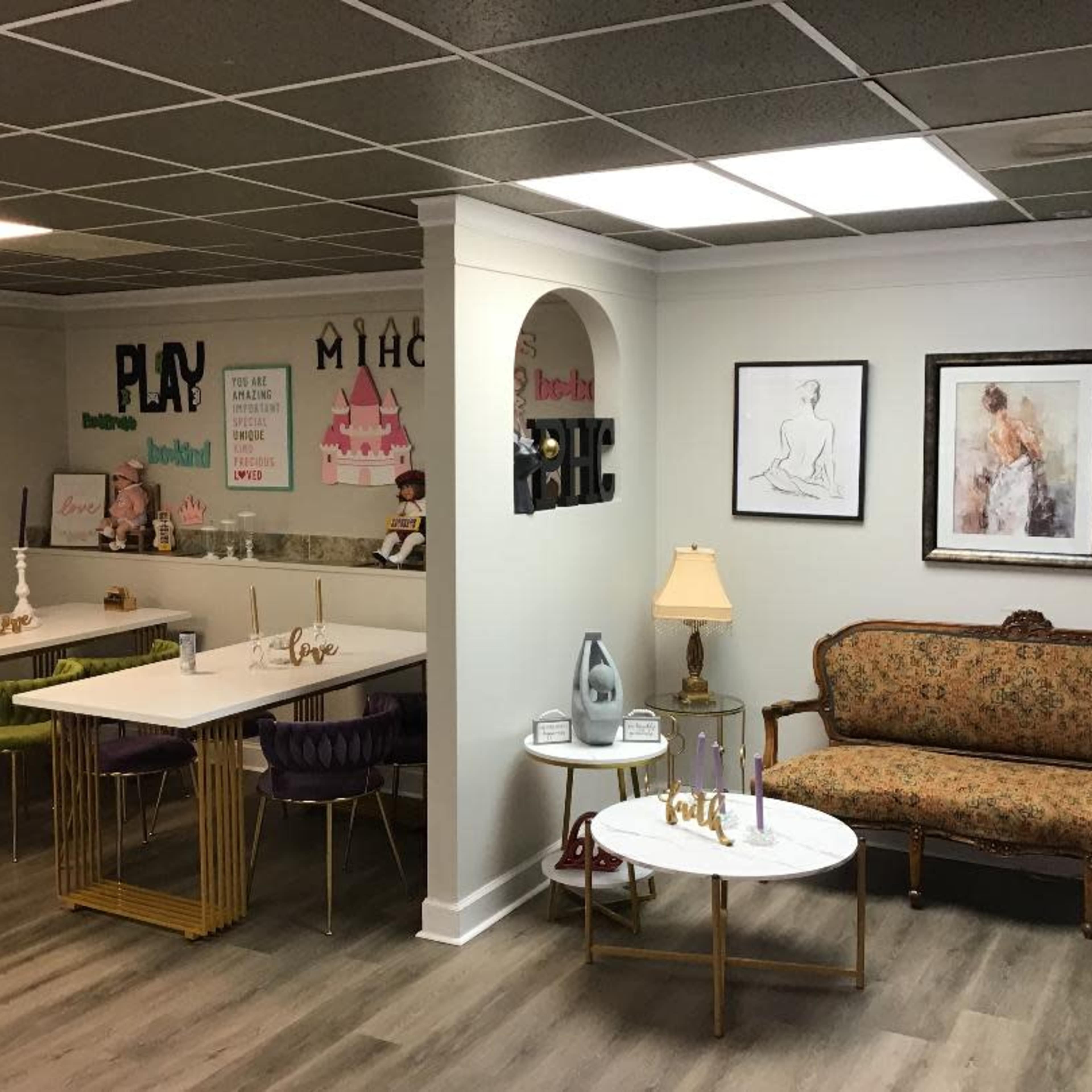 A stylish and organized indoor space with tables, artwork on the walls, and a decorative couch.