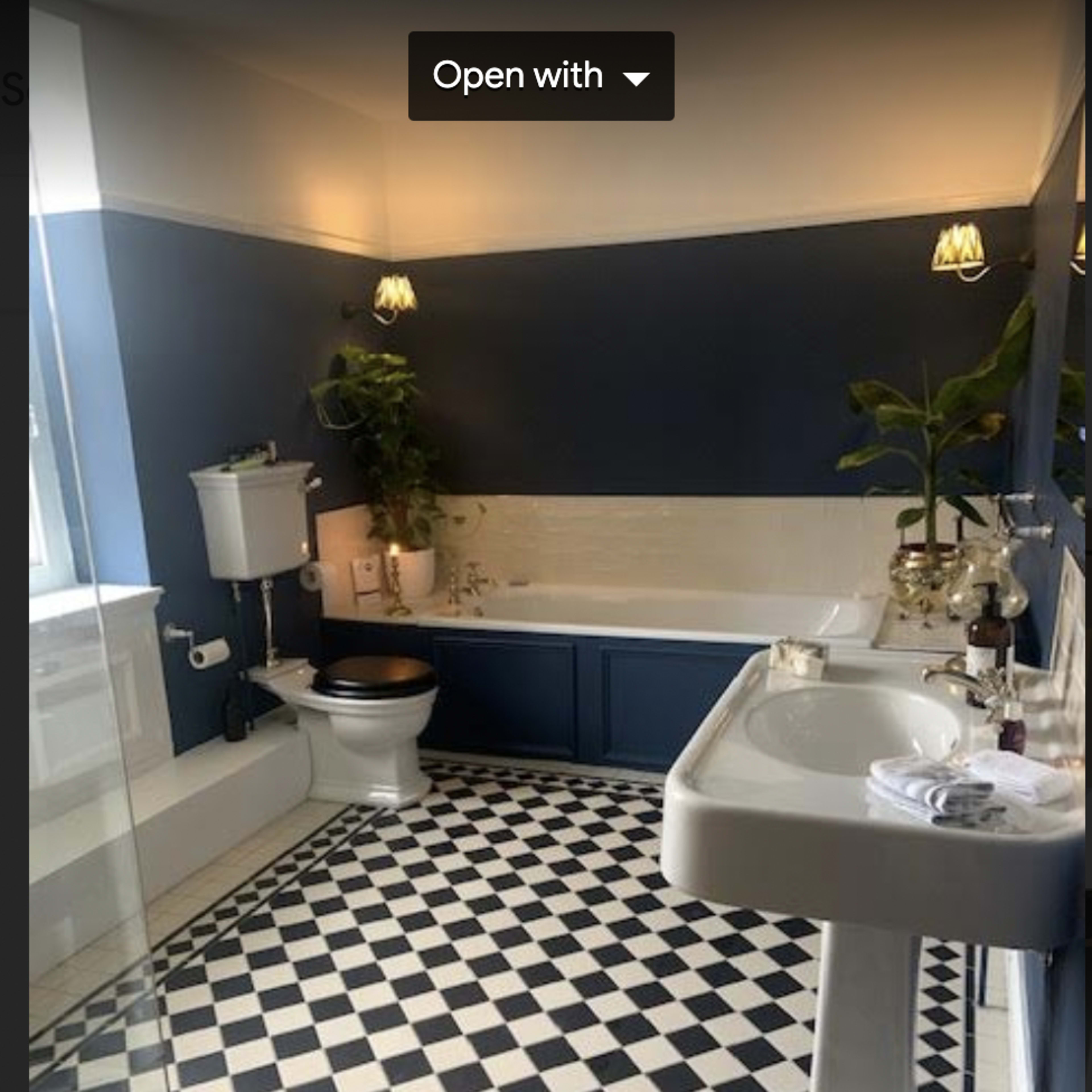 A modern bathroom featuring a bathtub, a toilet, a sink, and a checkered black and white floor.