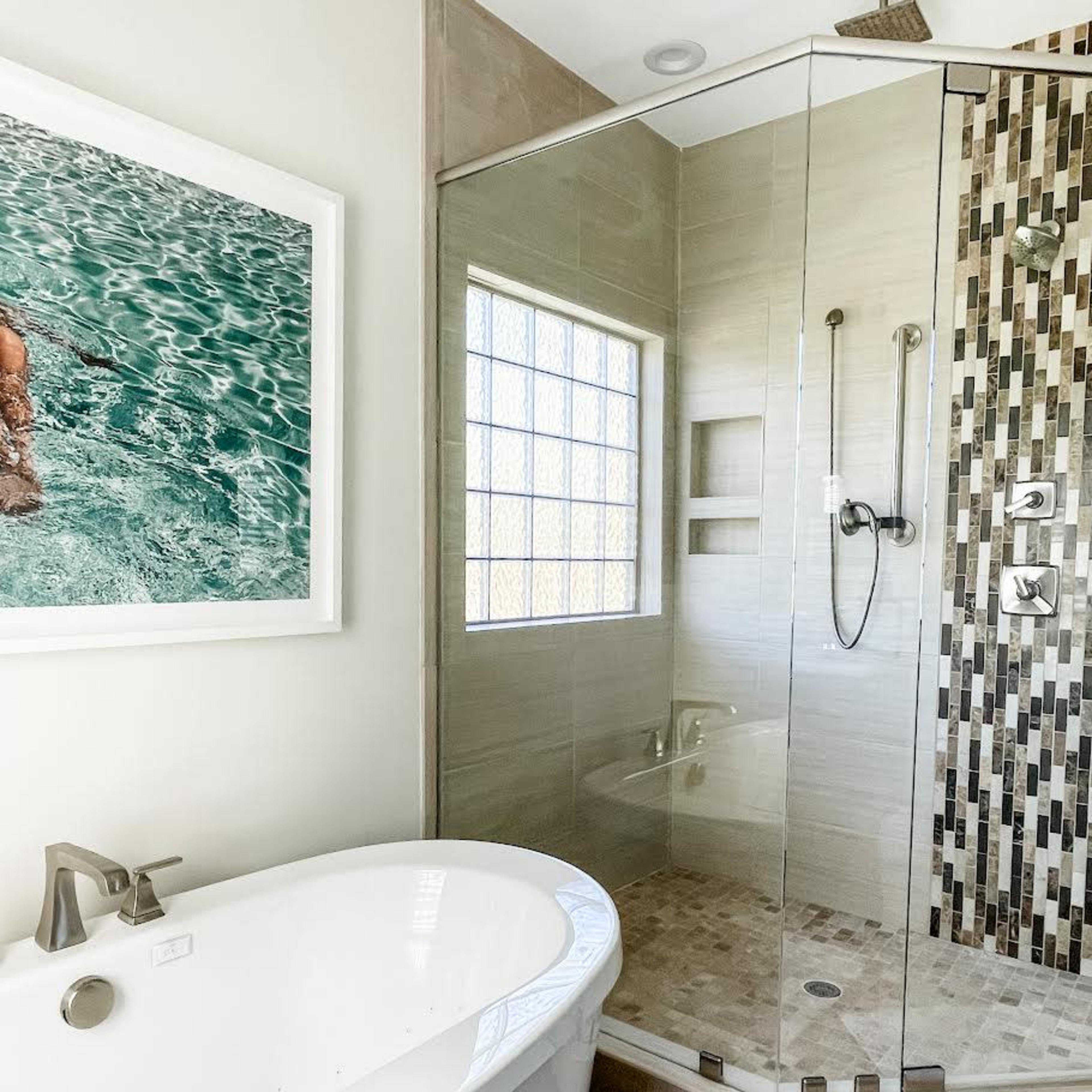 A modern bathroom featuring a freestanding tub and a glass-enclosed shower with tiled walls.