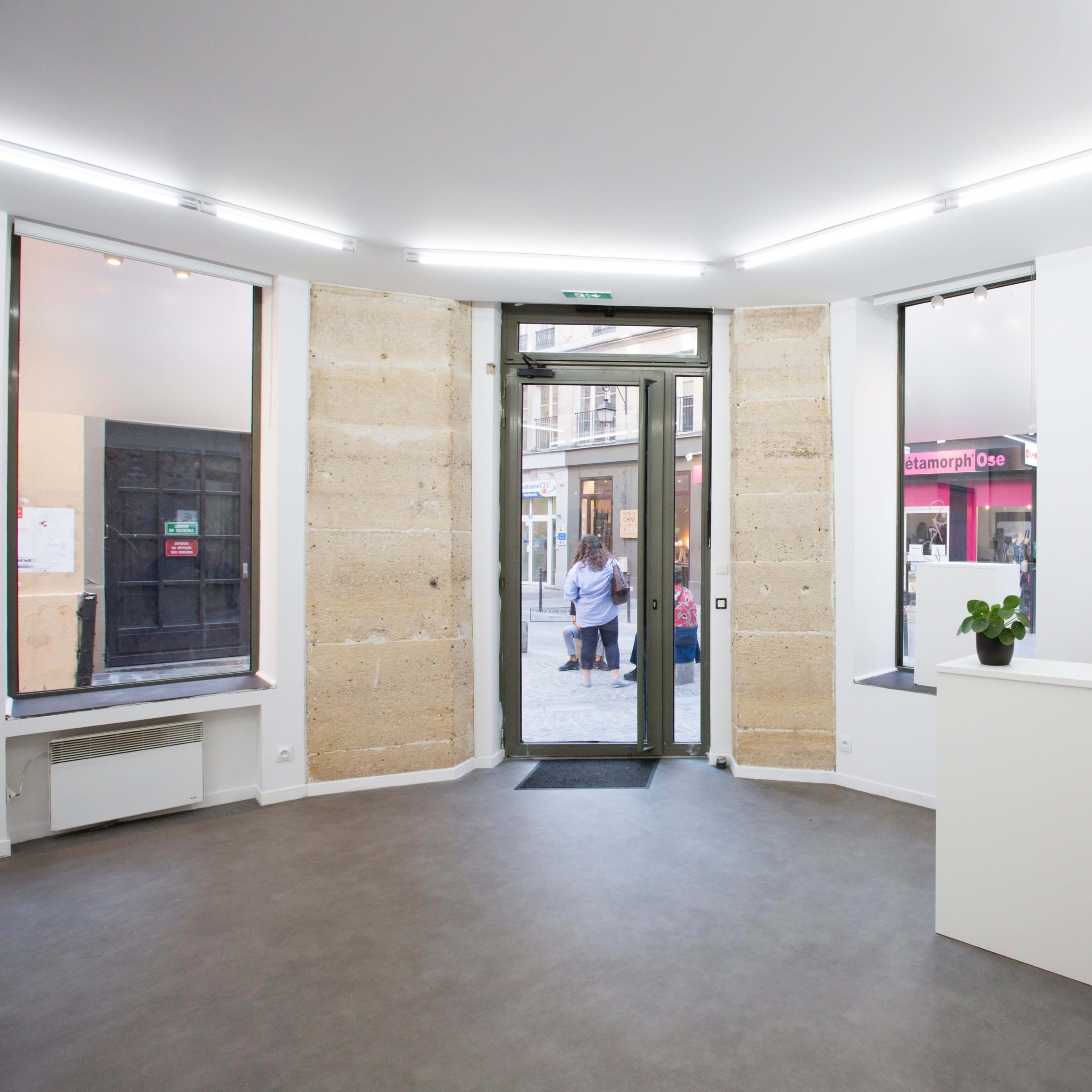 A modern, minimalistic reception area with a white desk and large windows allowing natural light.