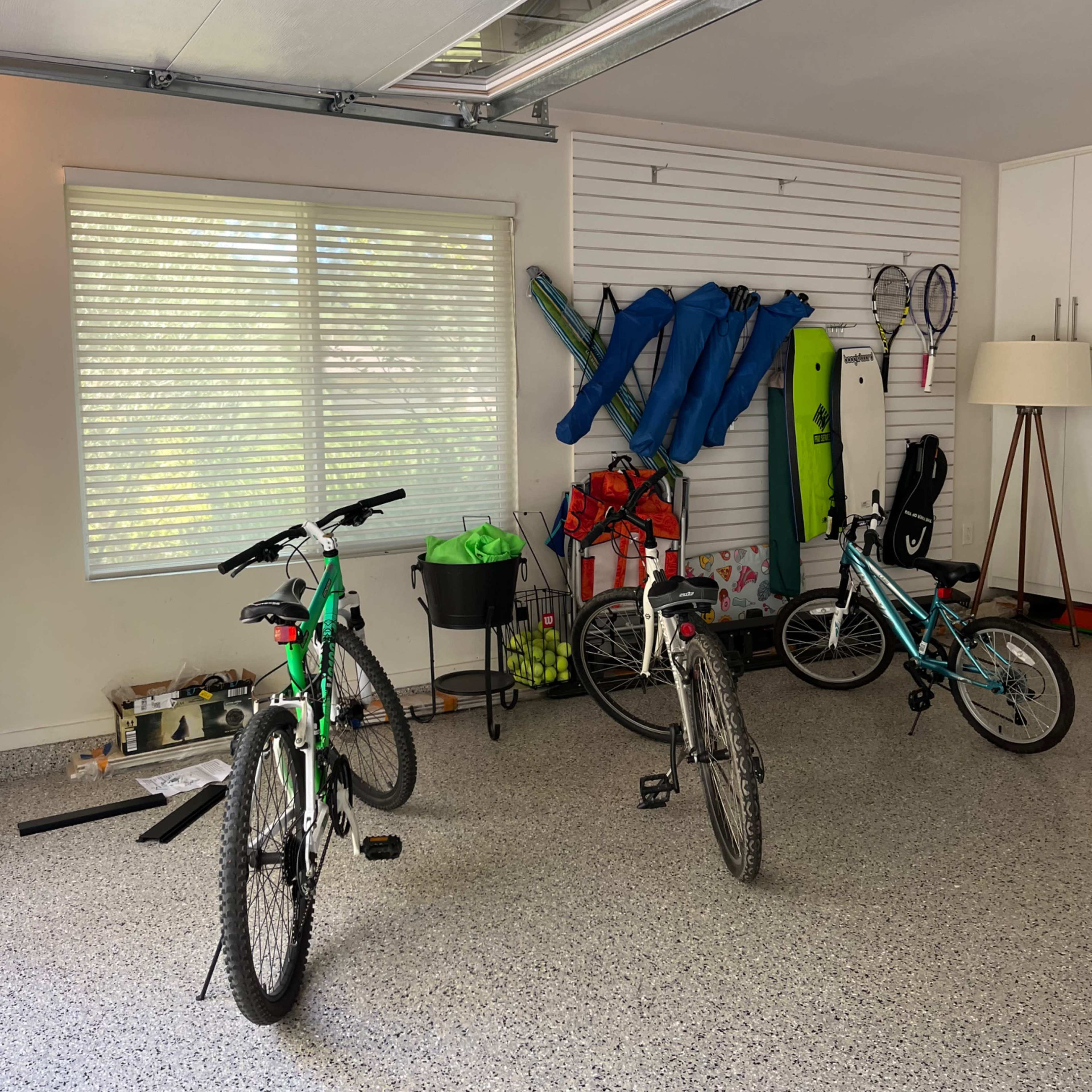 The garage contains two bicycles, sporting equipment on the wall, and a lamp in one corner.