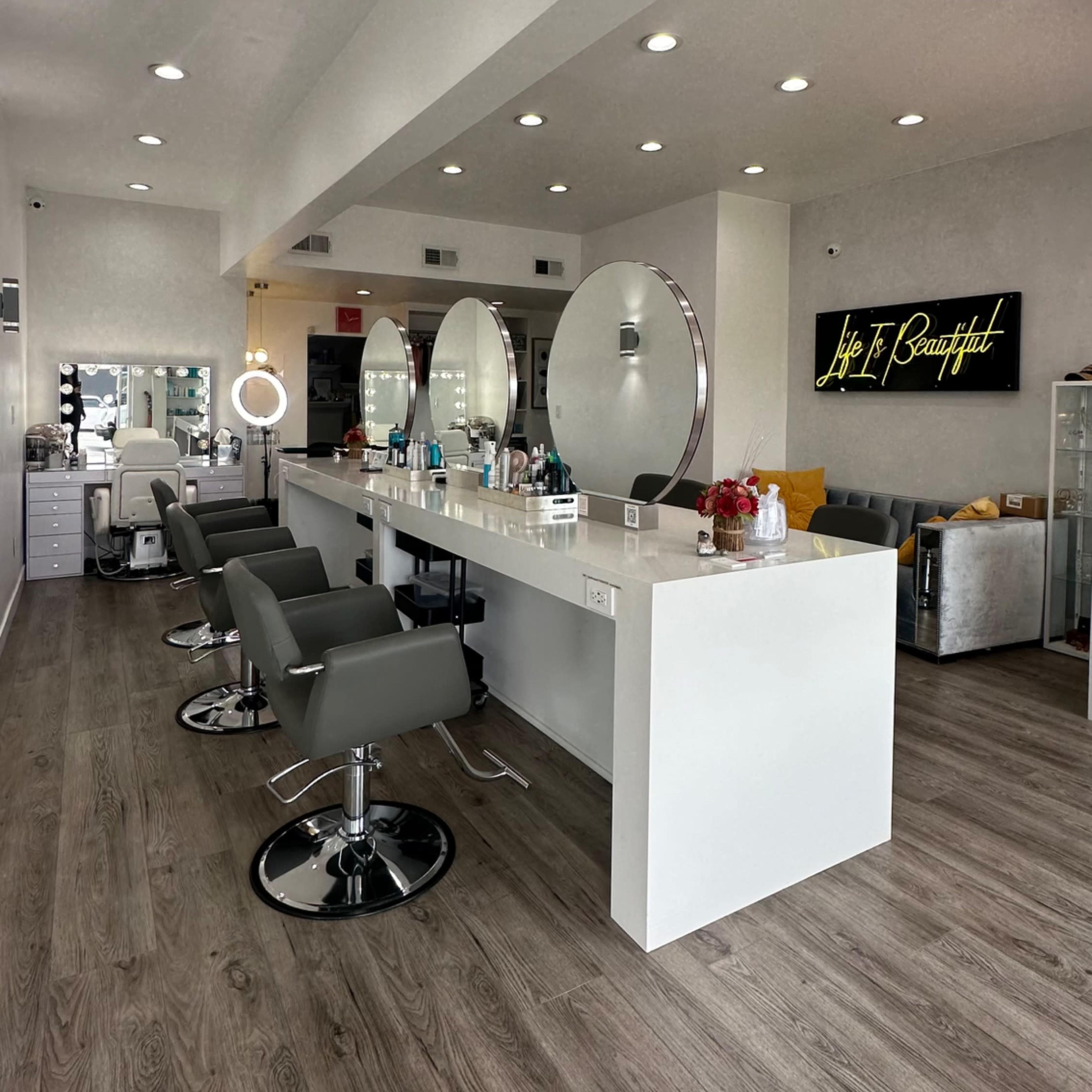 A modern hair salon with several styling stations, round mirrors, and sleek chairs.