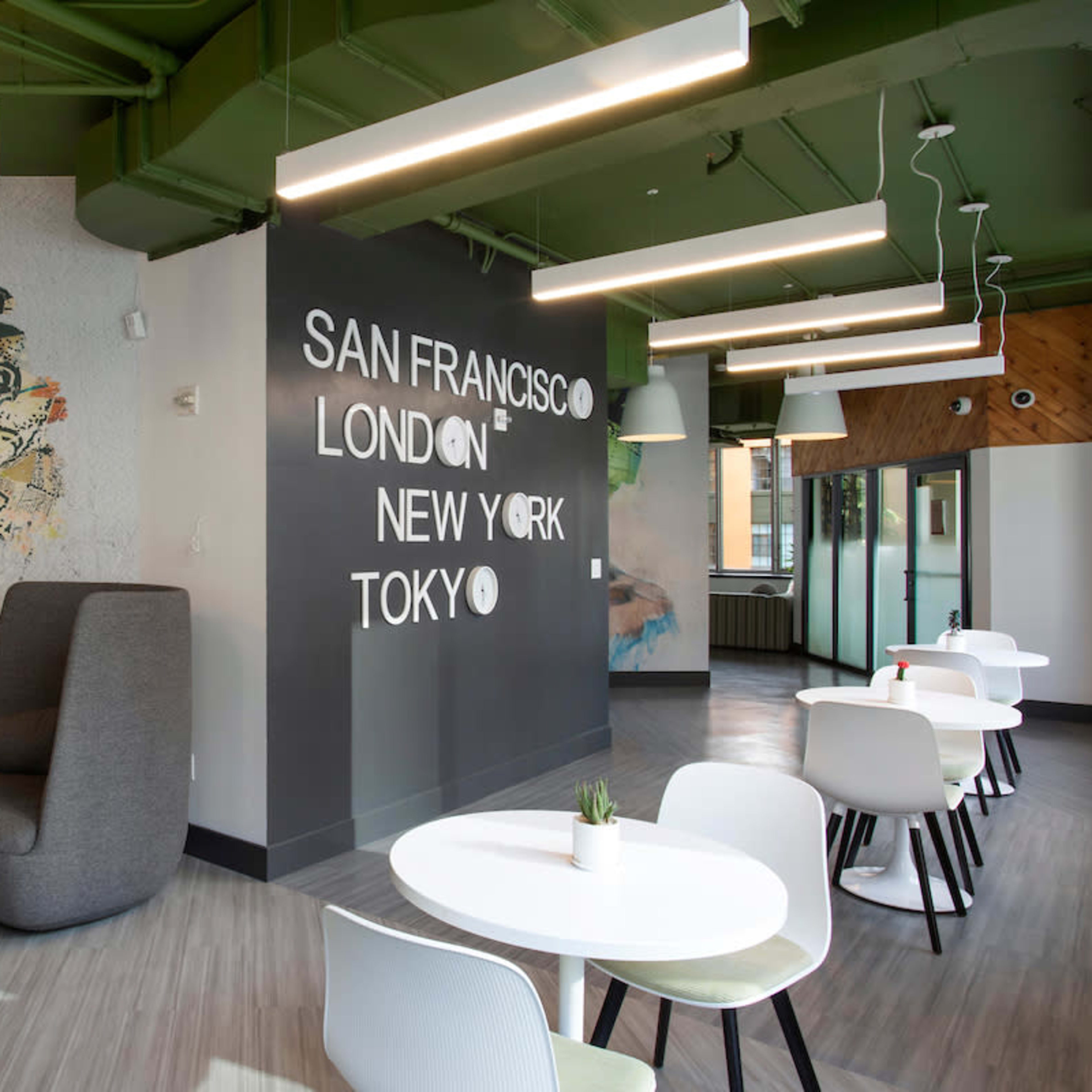 A modern interior workspace featuring a colorful mural, lounge seating, and tables arranged for collaboration.