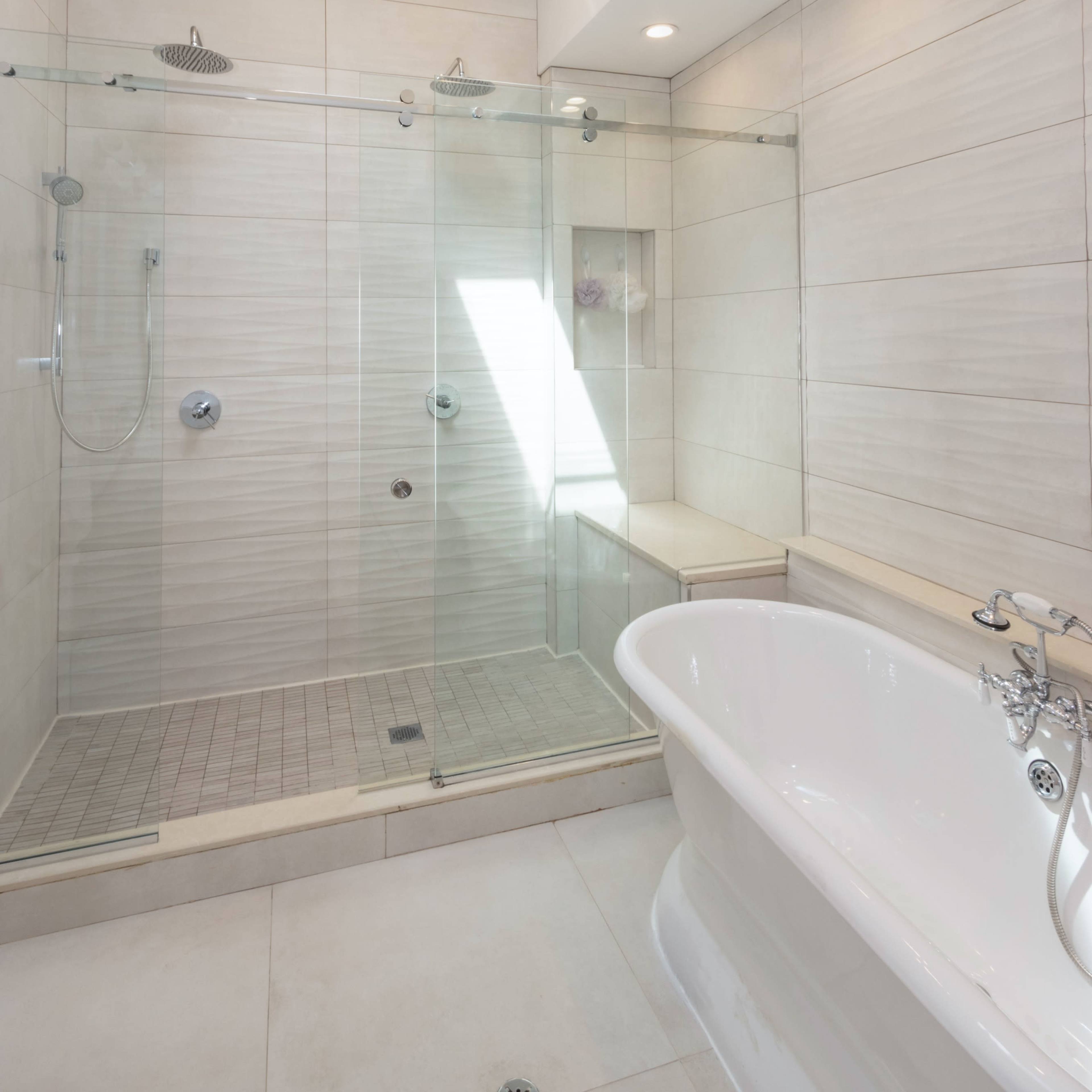 A modern bathroom features a glass-enclosed shower and a freestanding bathtub under a skylight.