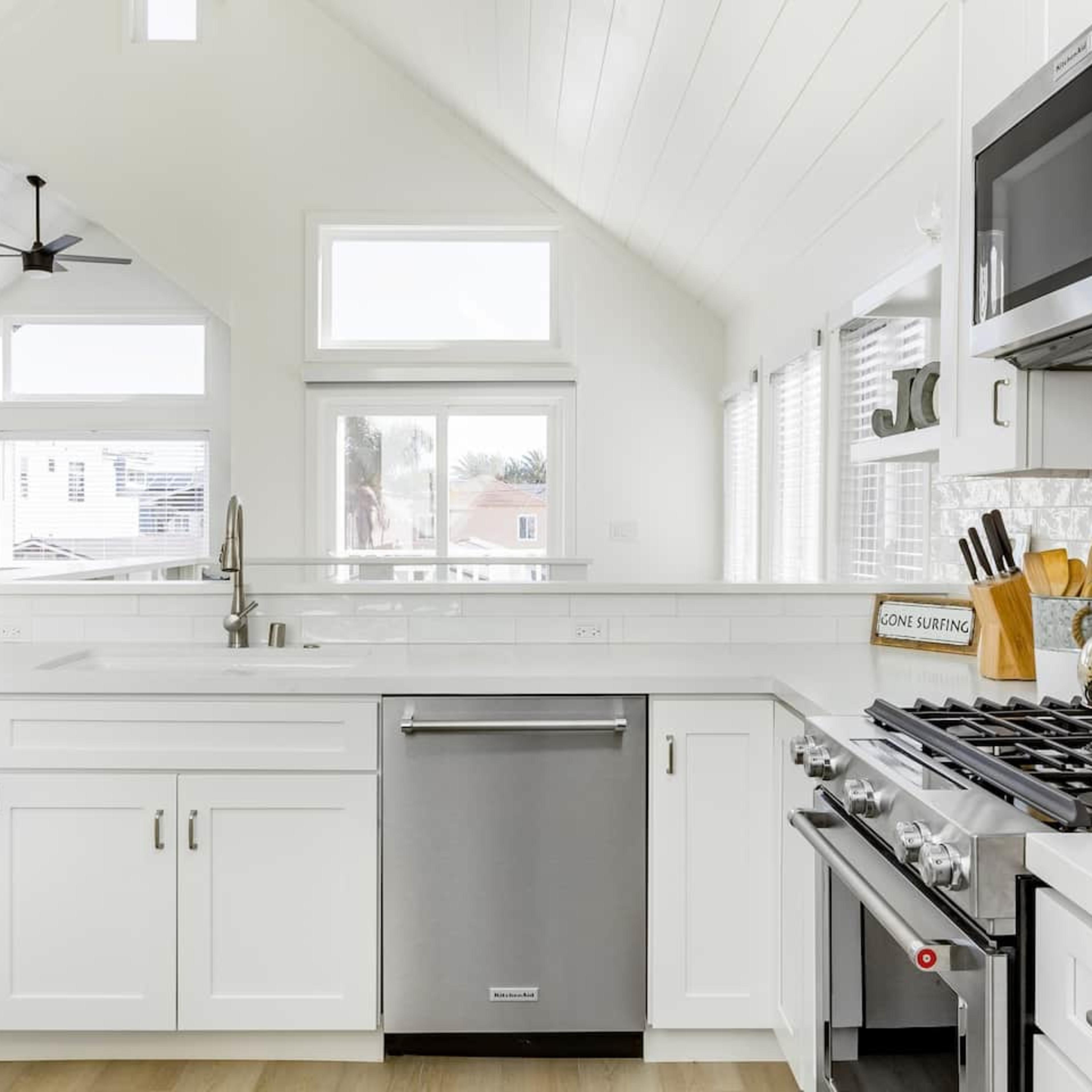 The kitchen features white cabinets, stainless steel appliances, and large windows that allow plenty of natural light.