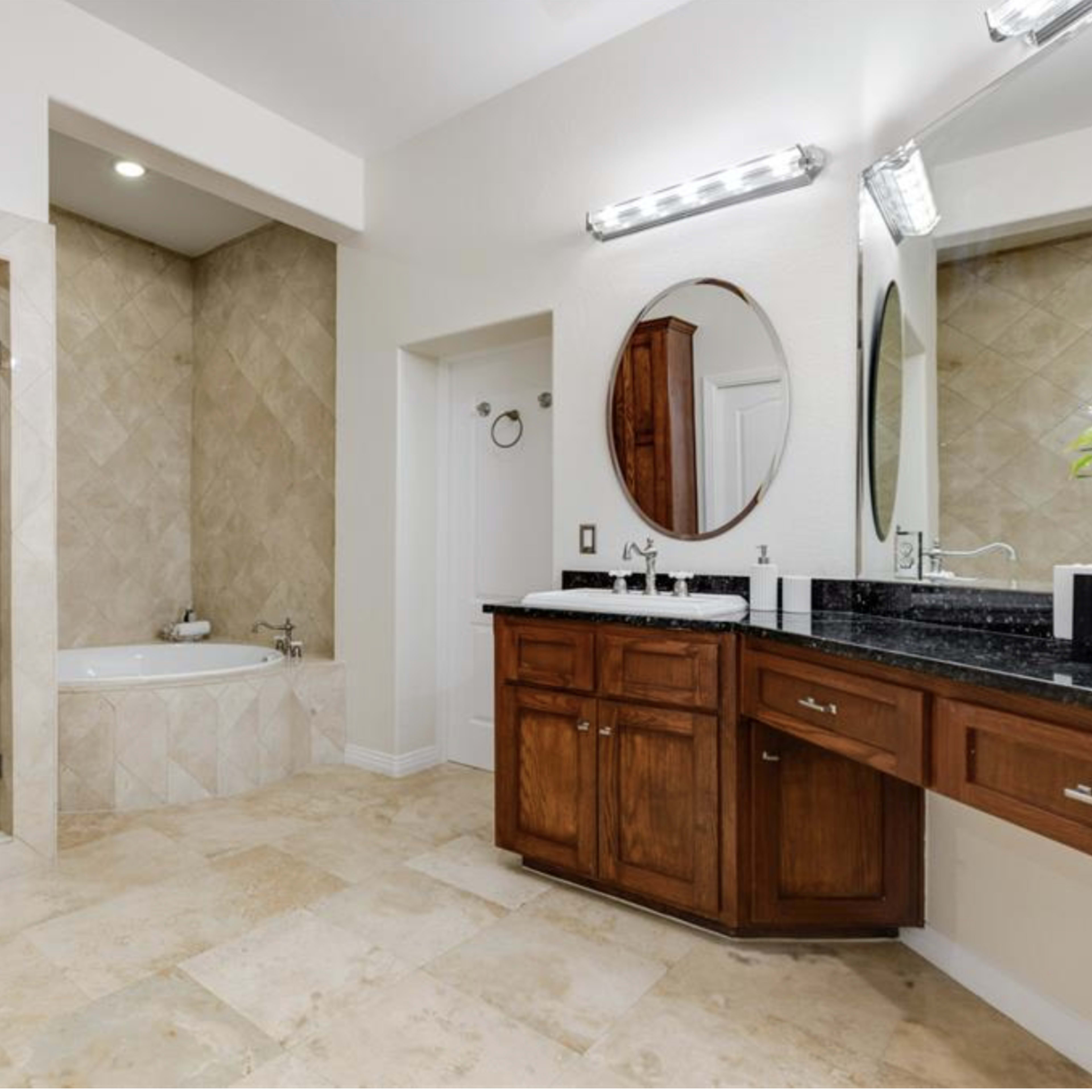 A spacious bathroom features a glass shower stall, a soaking tub, and a double-sink vanity with wooden cabinetry.