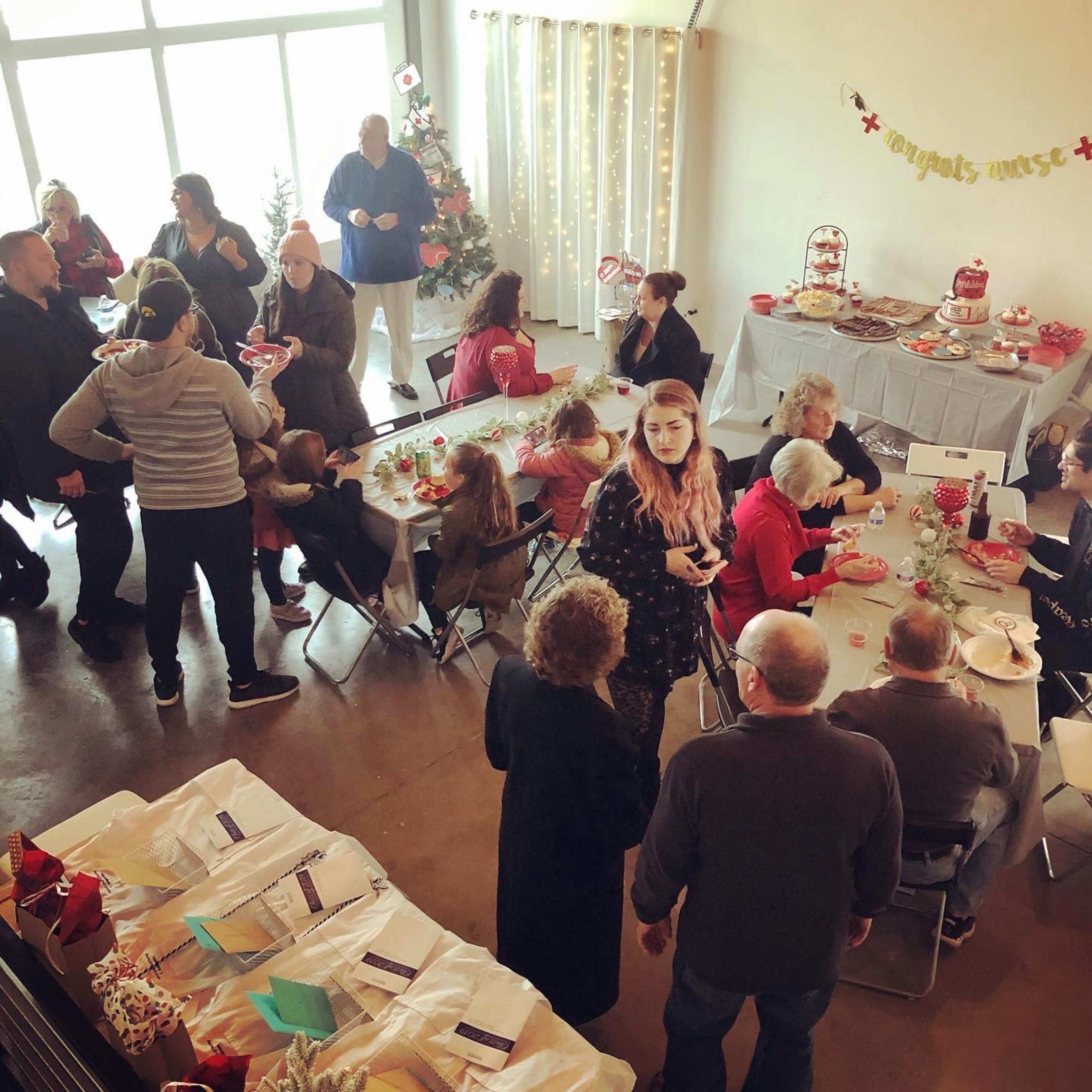 A festive gathering filled with people celebrating around tables decorated with food and holiday ornaments.
