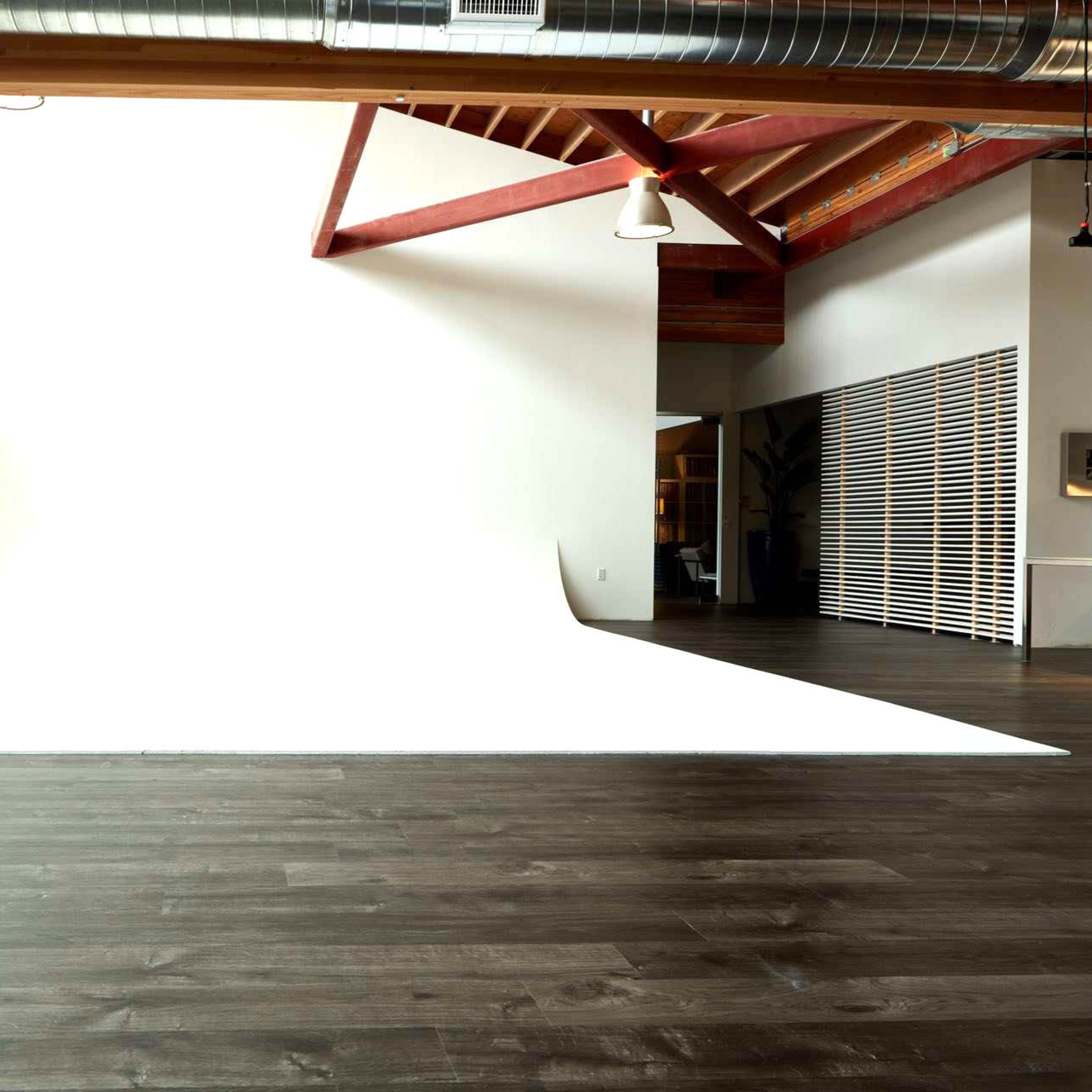 A spacious studio with a large white backdrop and wooden floors.