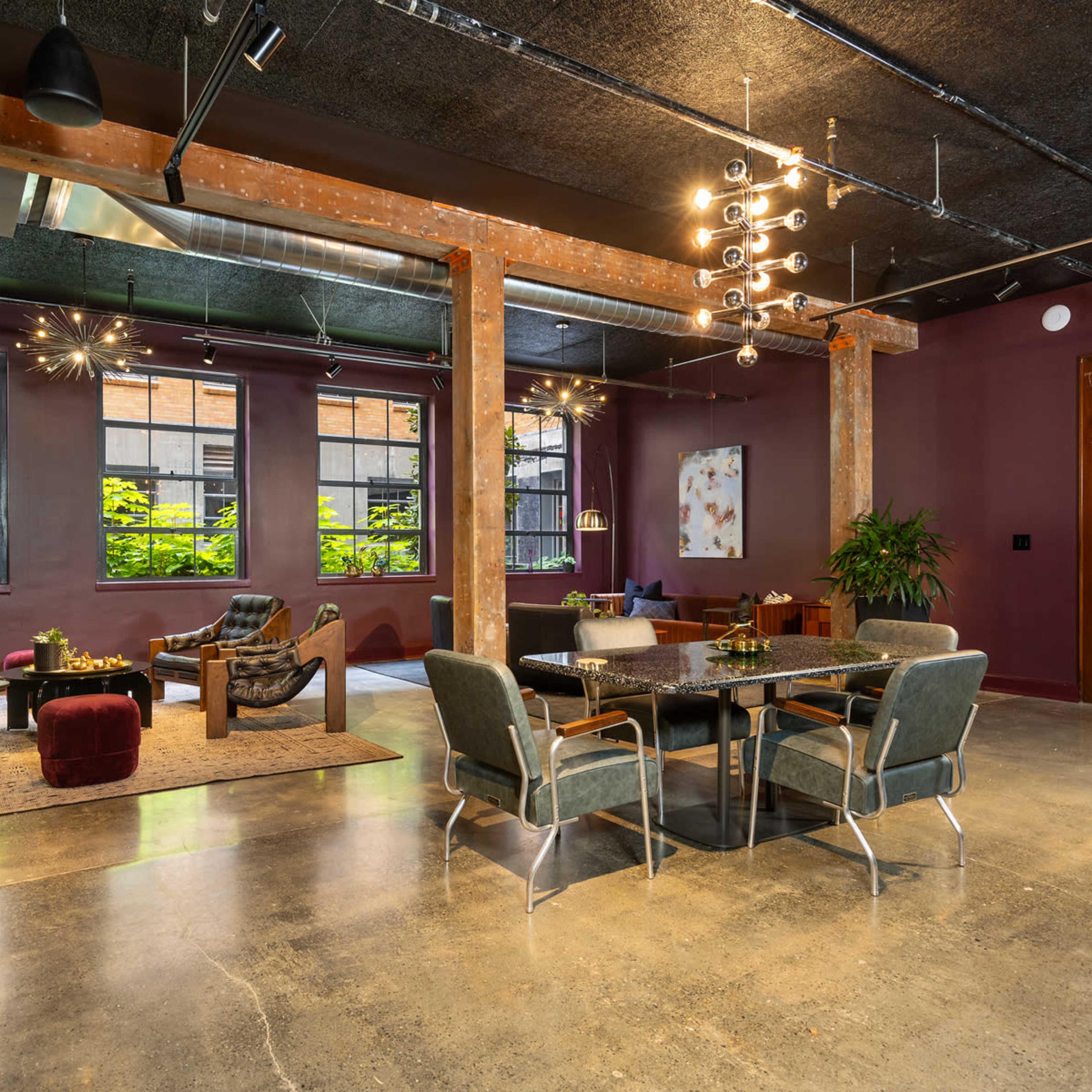 A spacious, modern living area featuring a mix of seating options, large windows, and exposed brick walls.