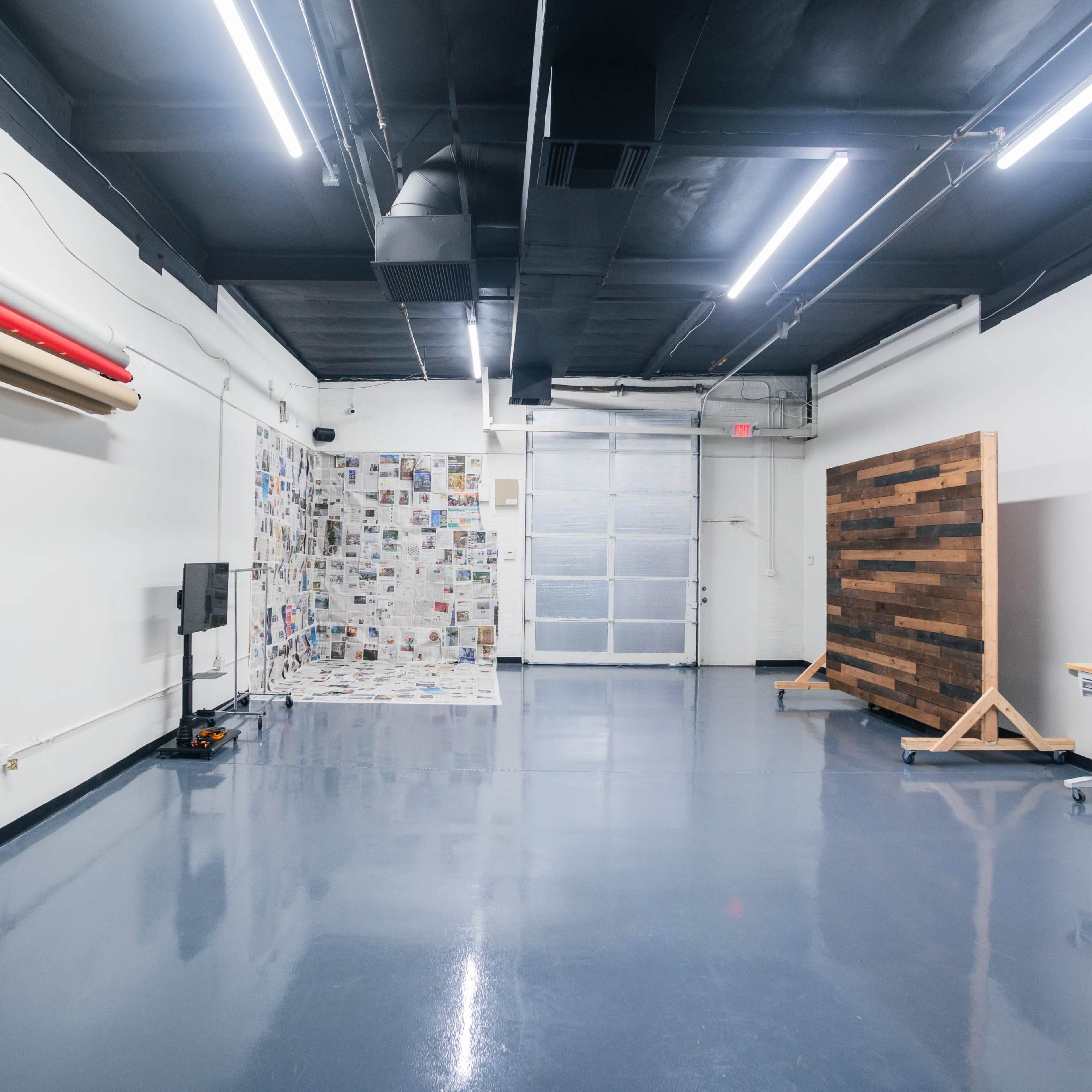 A spacious, well-lit indoor area with various wall textures, a wooden partition, and equipment along one side.