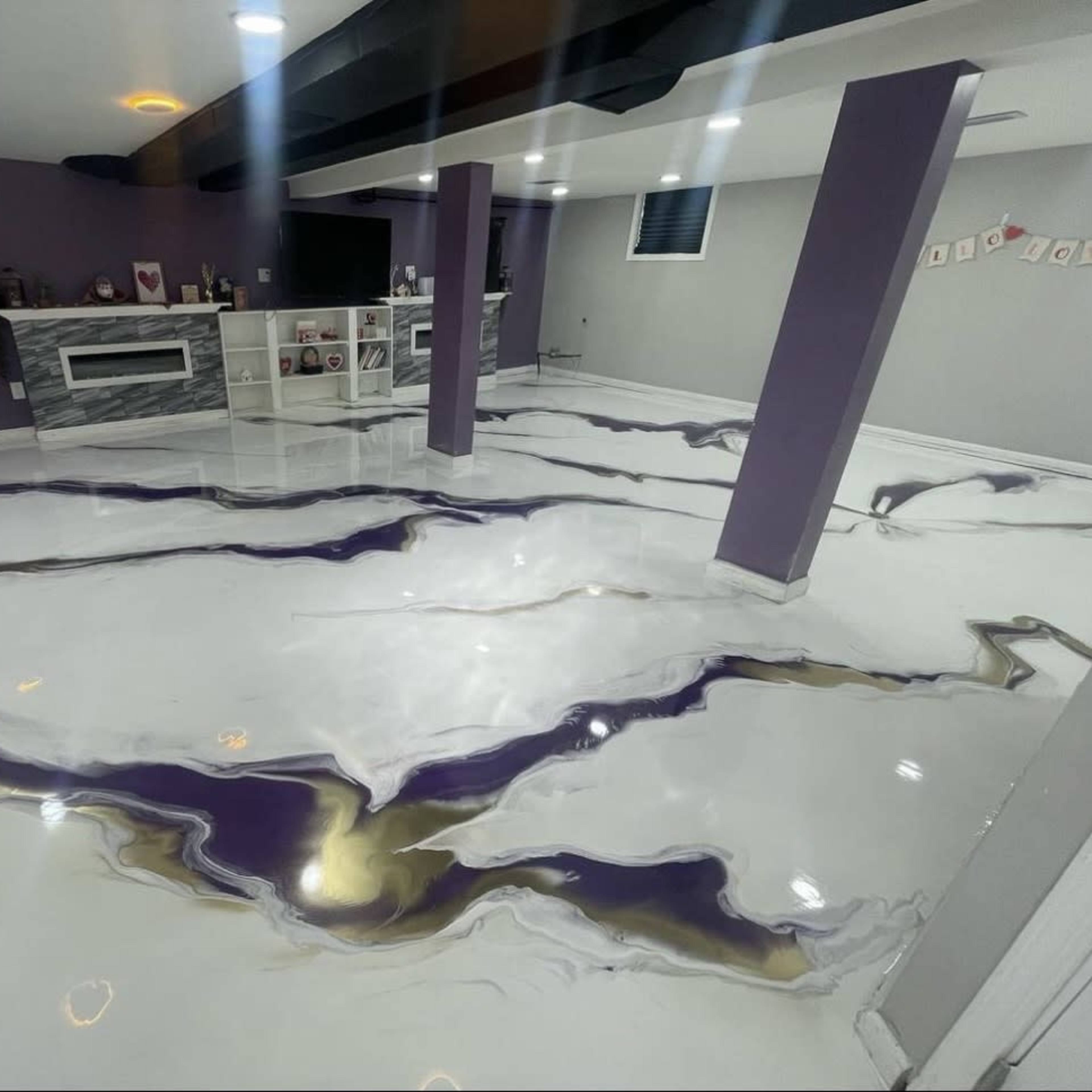 A finished basement with a polished, marbled floor featuring white, purple, and gold colors, along with light gray walls and a modern entertainment area.
