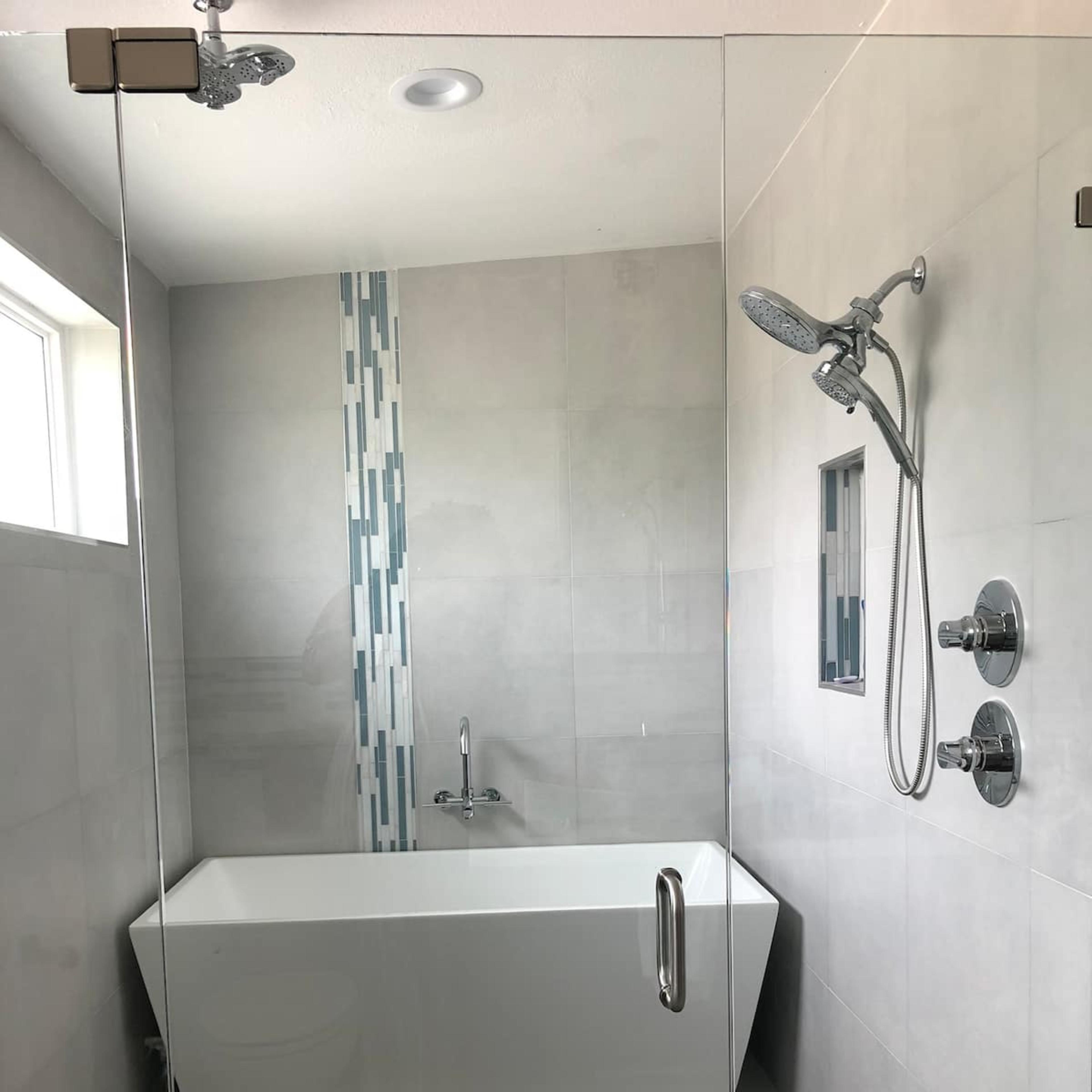 A modern bathroom featuring a glass-enclosed shower with a freestanding bathtub and a wooden slatted floor.