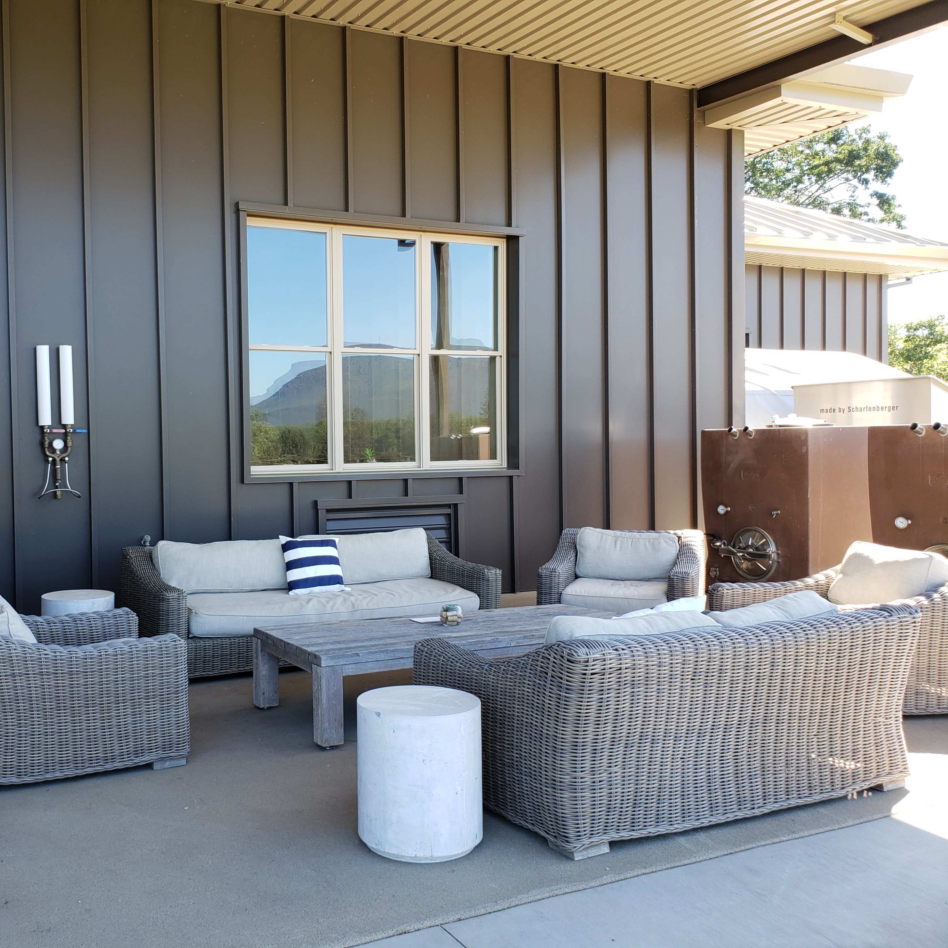 A furnished outdoor seating area with a coffee table and a view of a mountain through a large window.