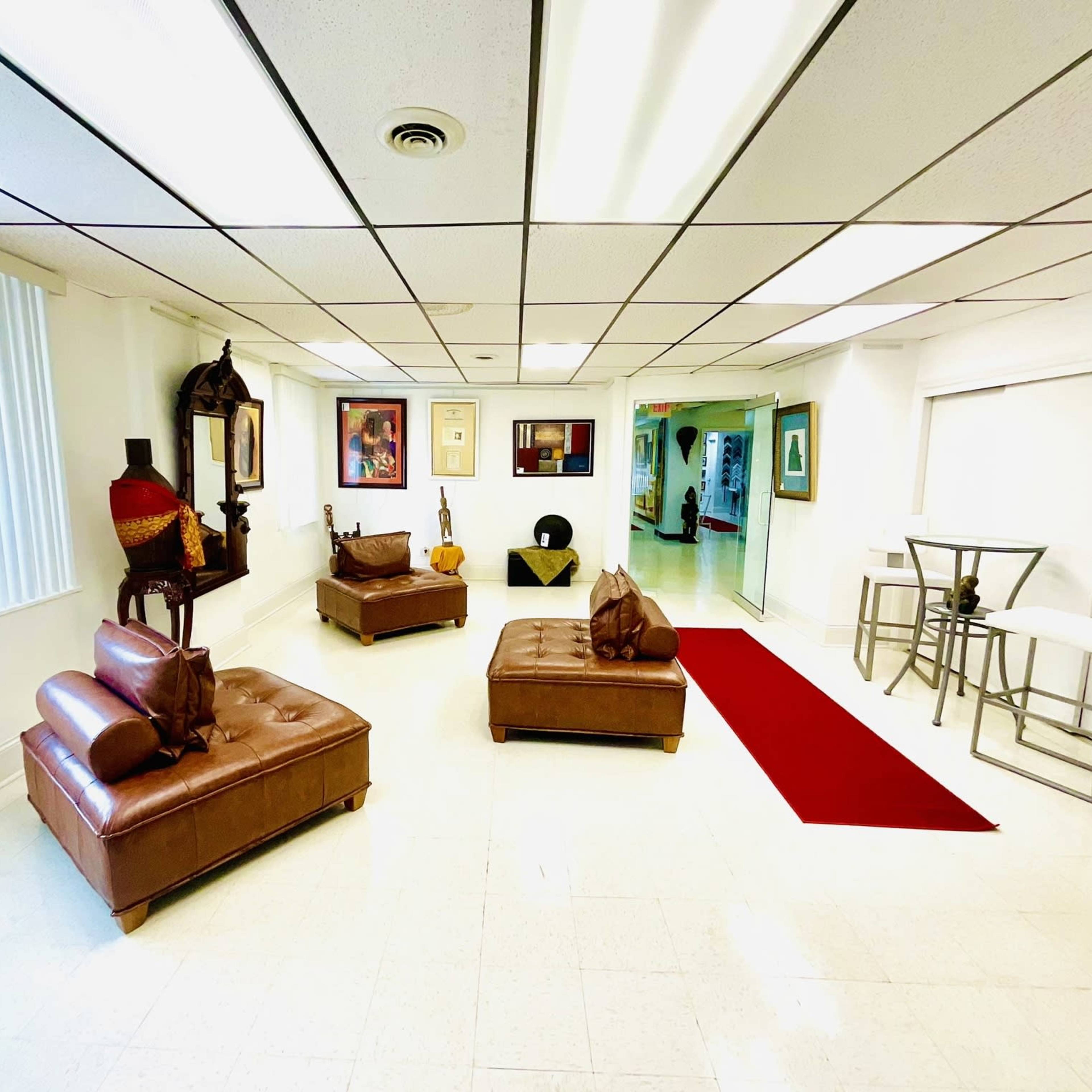 A spacious room with two brown leather sofas, a red area rug, and a small dining table with white chairs.