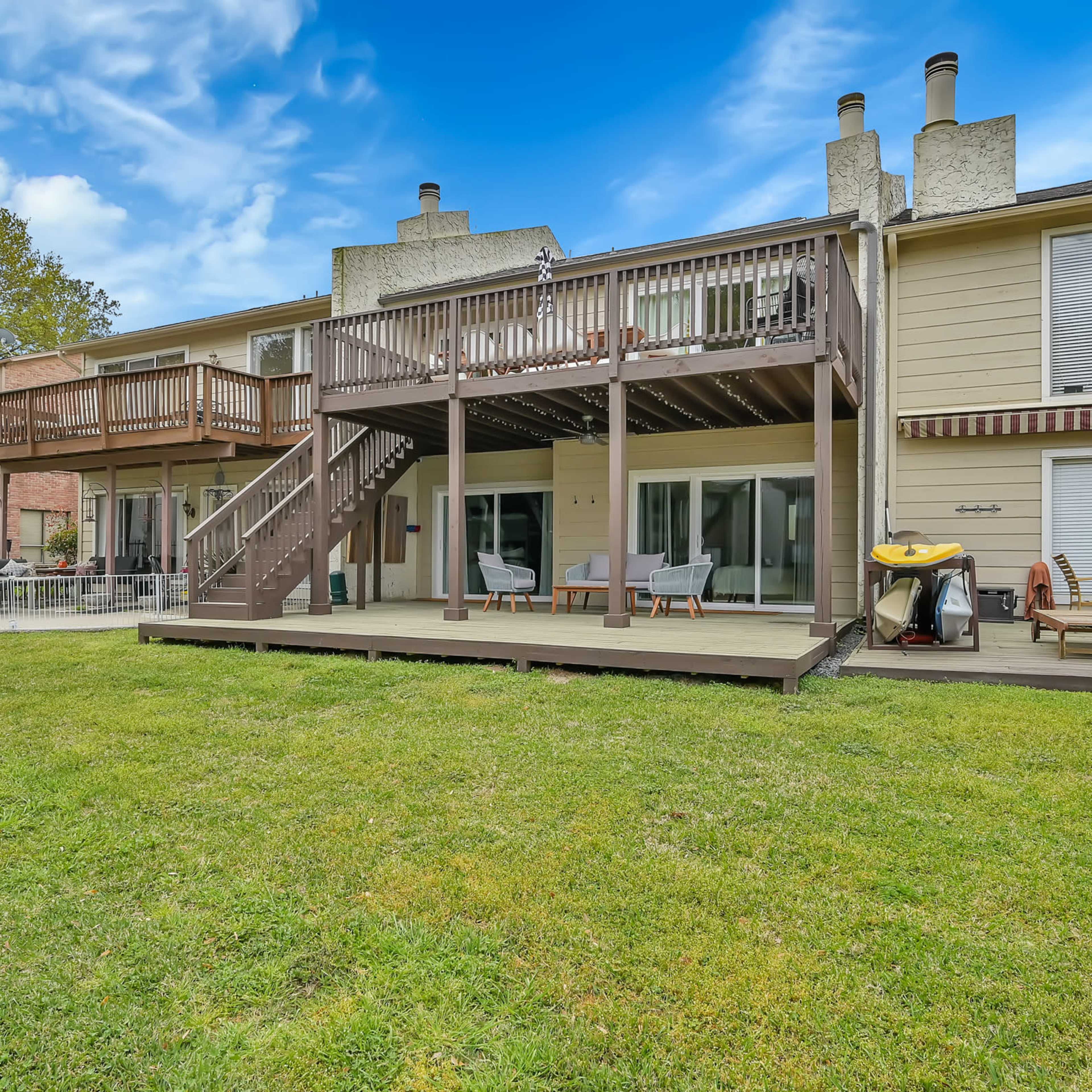 A spacious backyard with a multi-level deck attached to a two-story residential building.