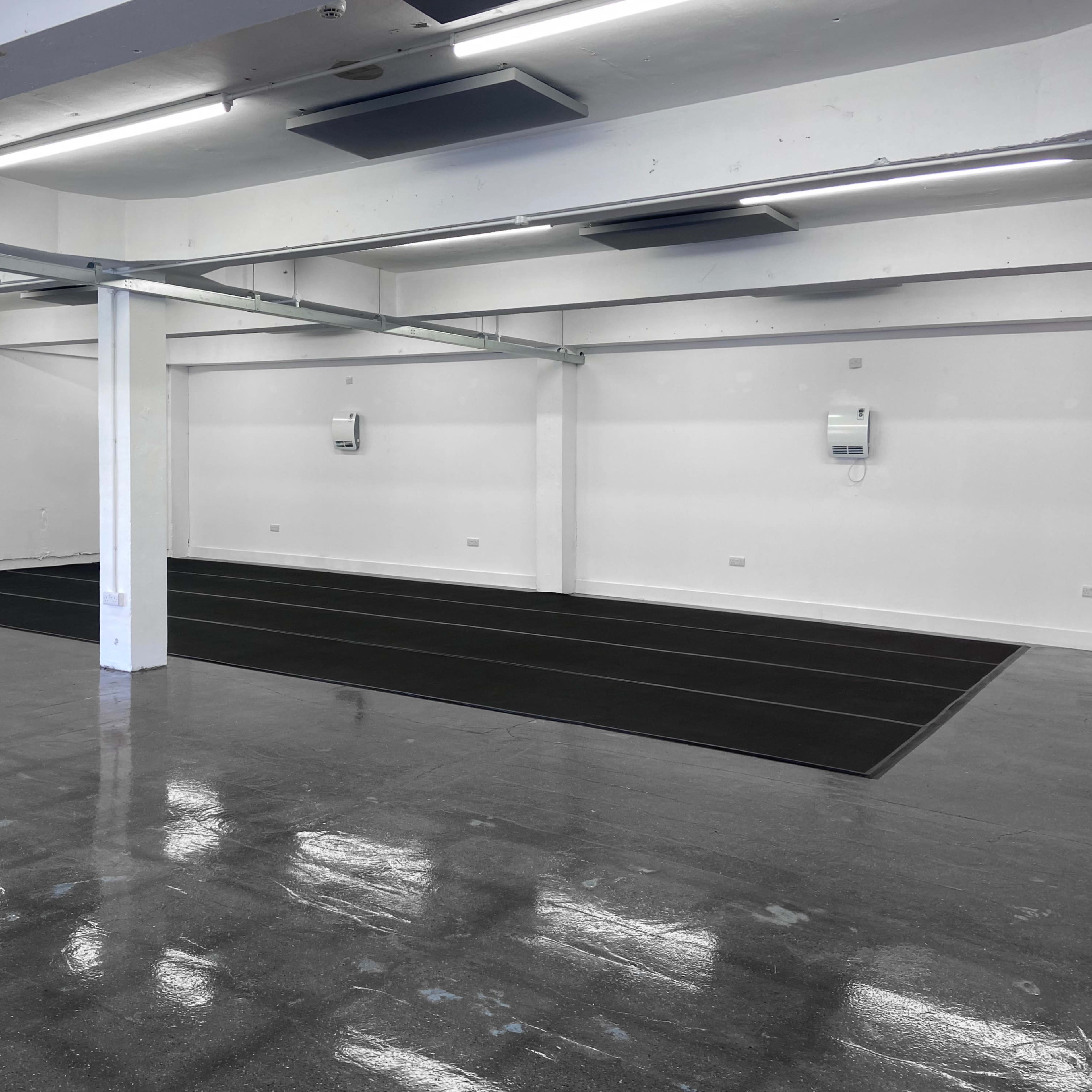 A spacious, empty interior with polished flooring and two black mat areas on the floor.