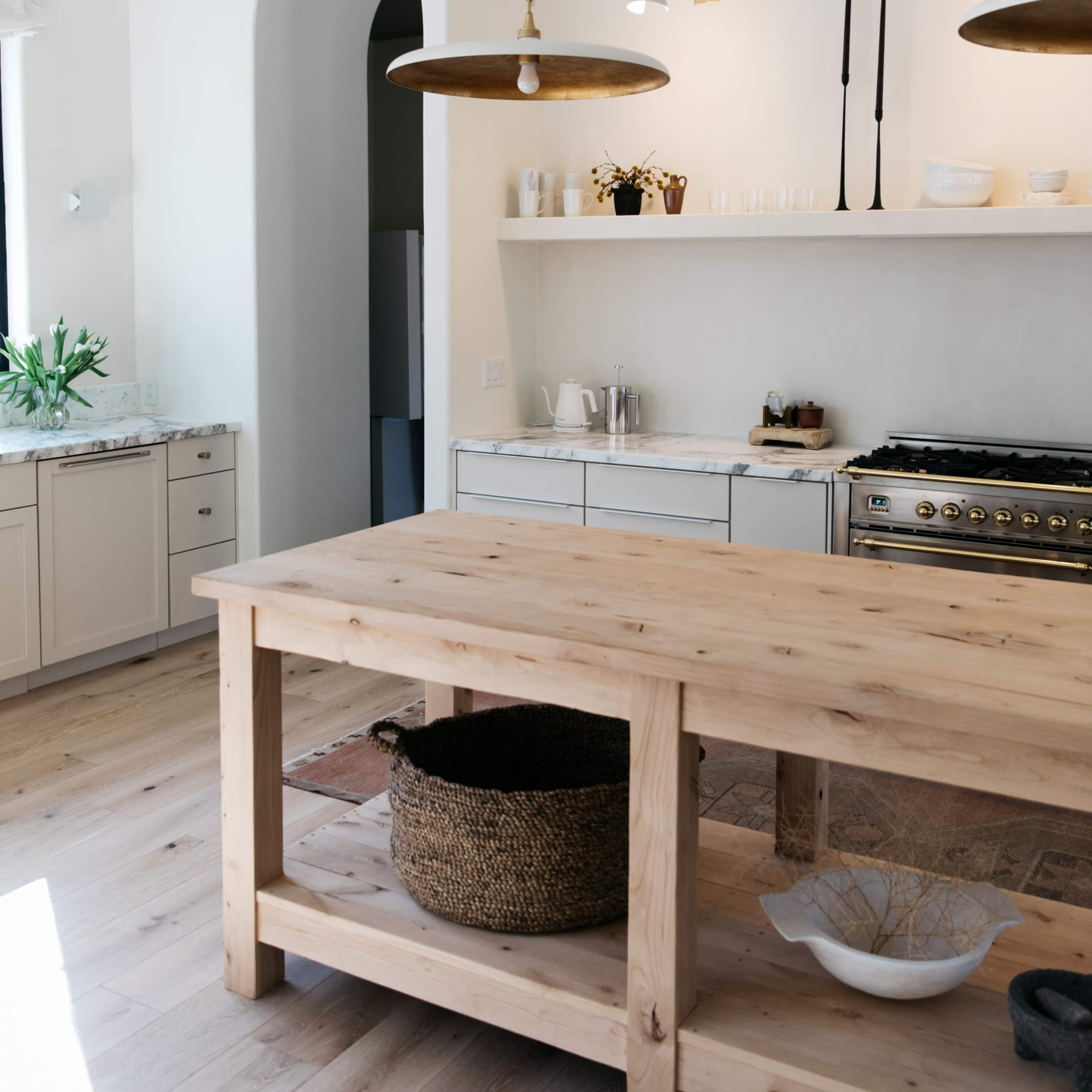 A modern kitchen with a wooden island, pendant lights, and open shelving above the countertop.