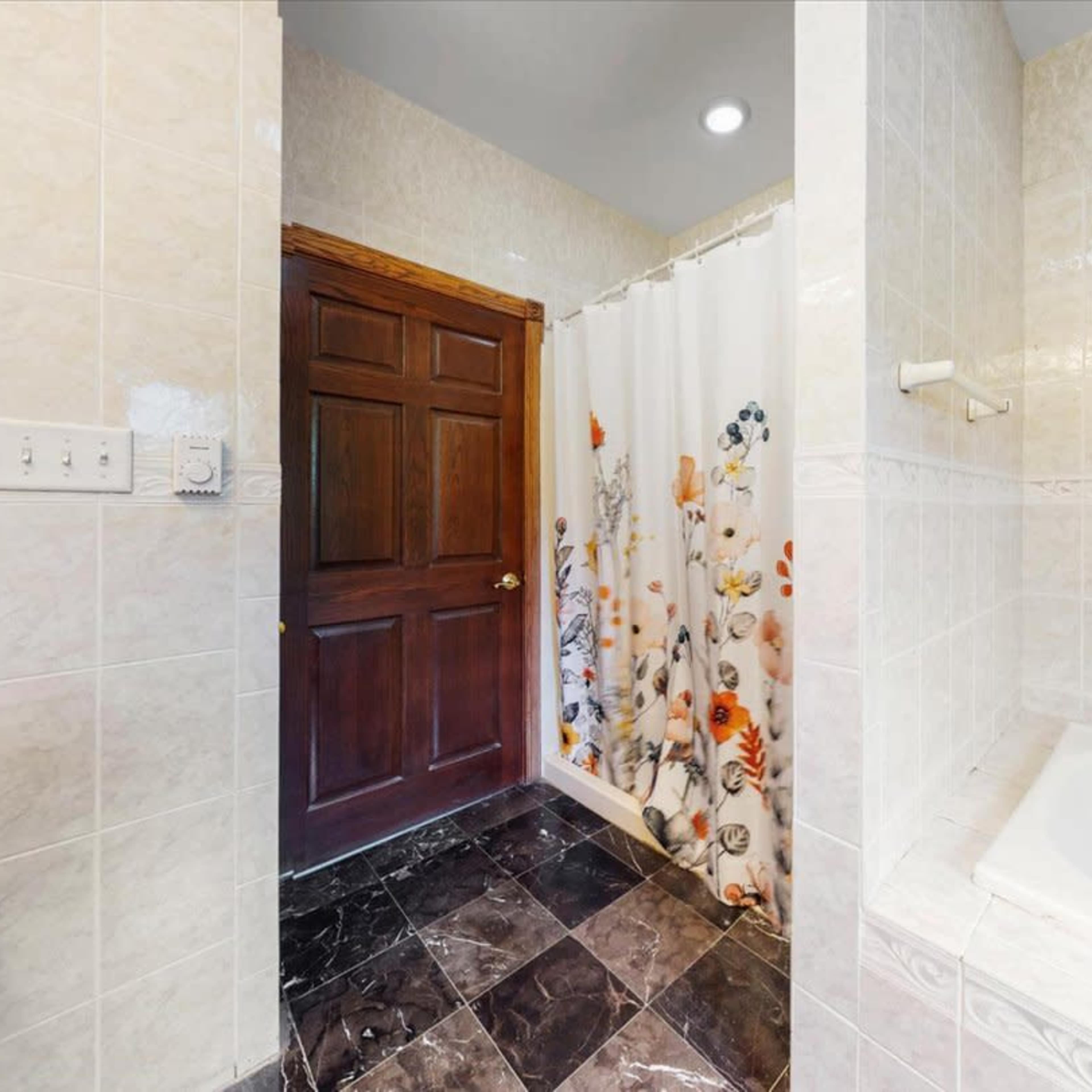 A bathroom with a bathtub, a shower curtain, and a door on one wall.