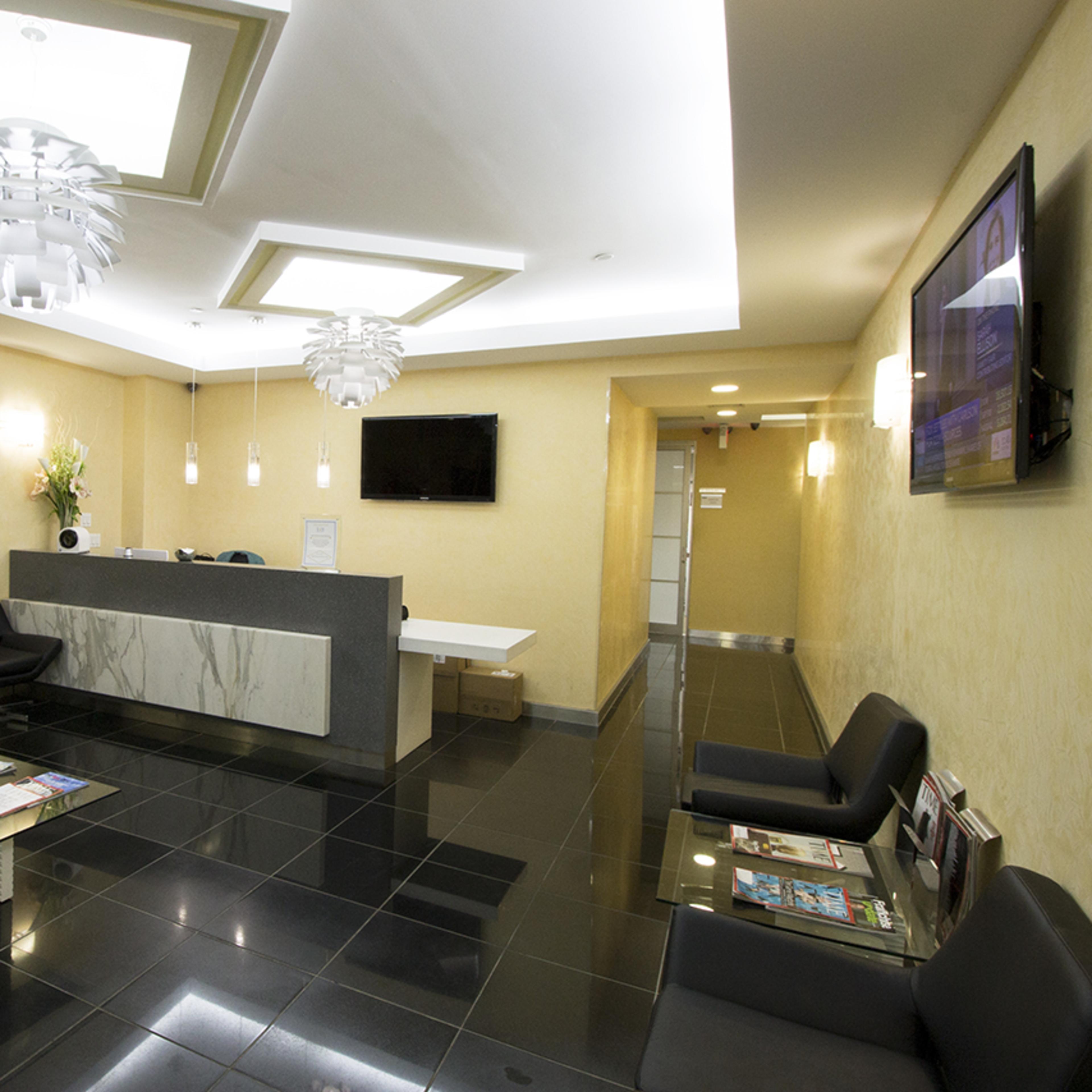 A modern reception area with sleek black chairs, a marble-front desk, and contemporary lighting fixtures.