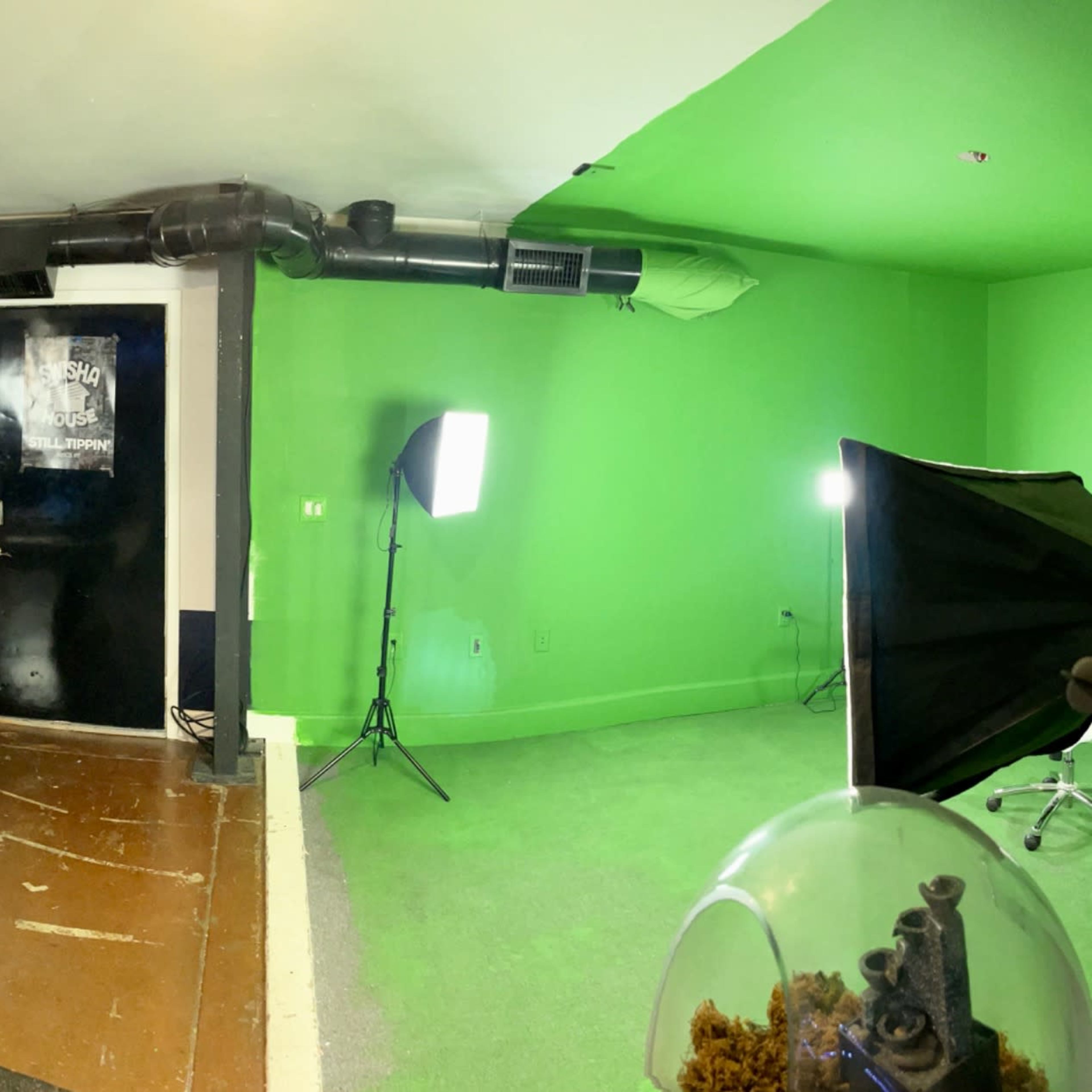 A spacious room featuring a pool table, photography lighting setups, and a green screen on one wall.