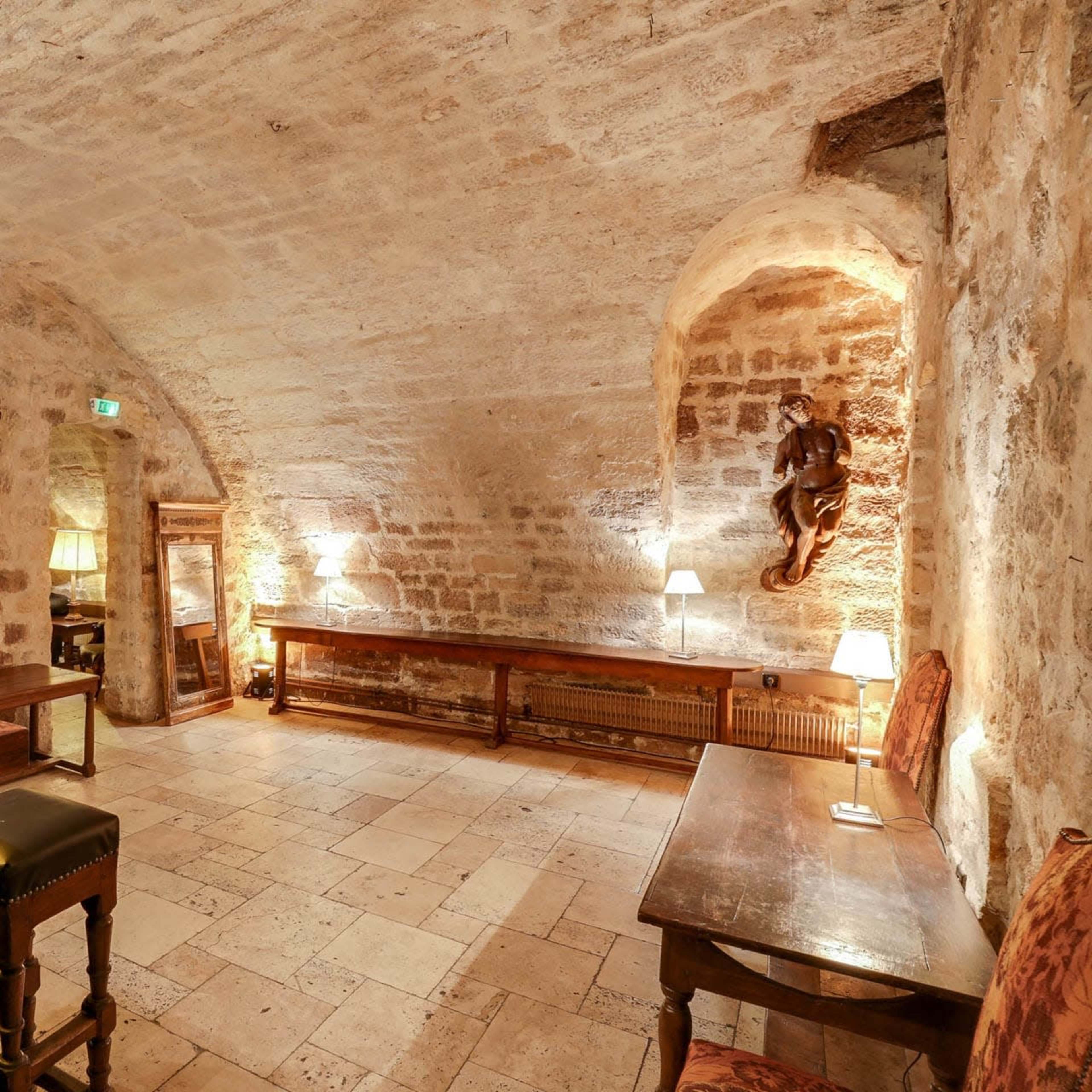 The image depicts a stone-walled cellar with a bar, wooden furnishings, and various lighting fixtures.