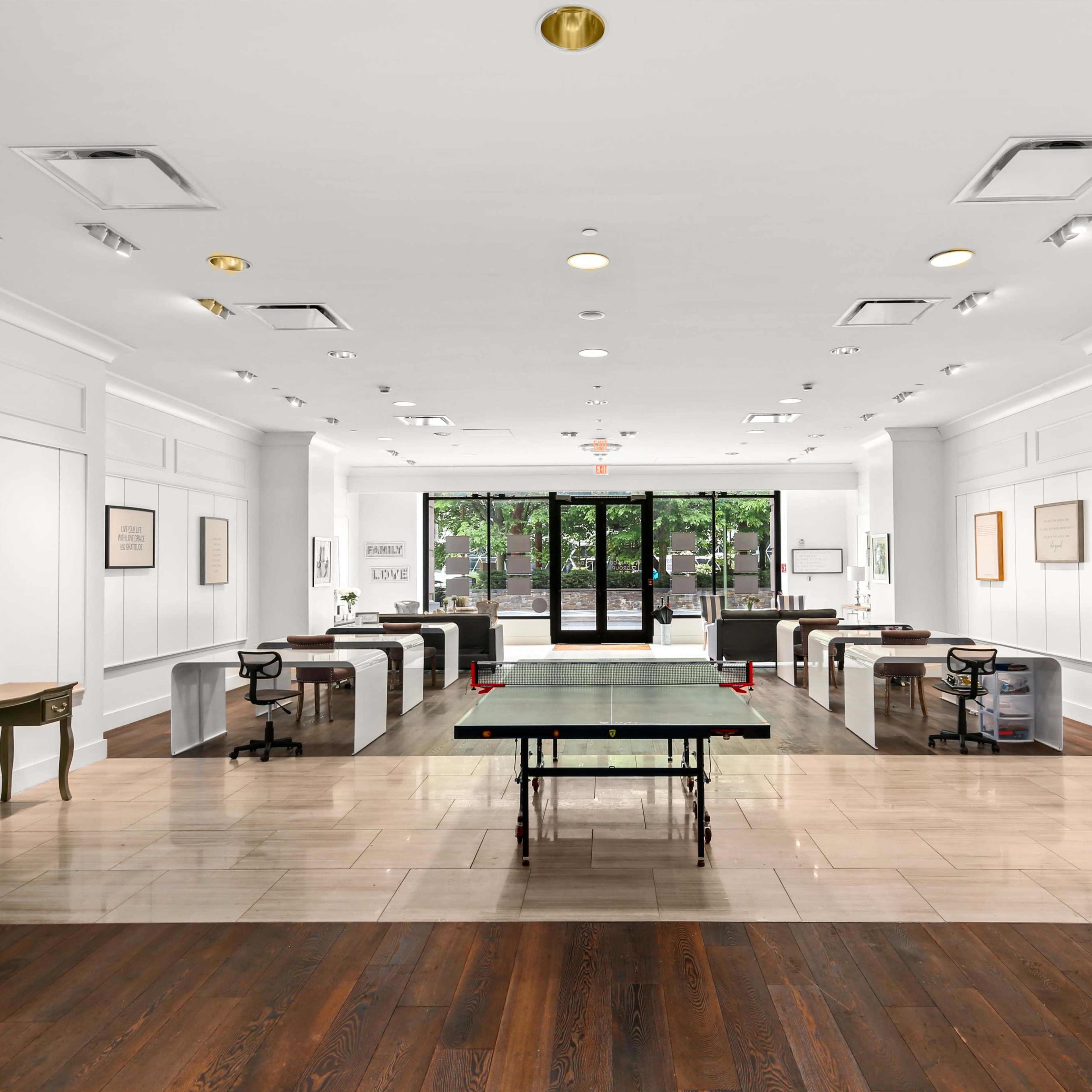 A spacious, modern office with a ping pong table in the center and several desks arranged along the walls.