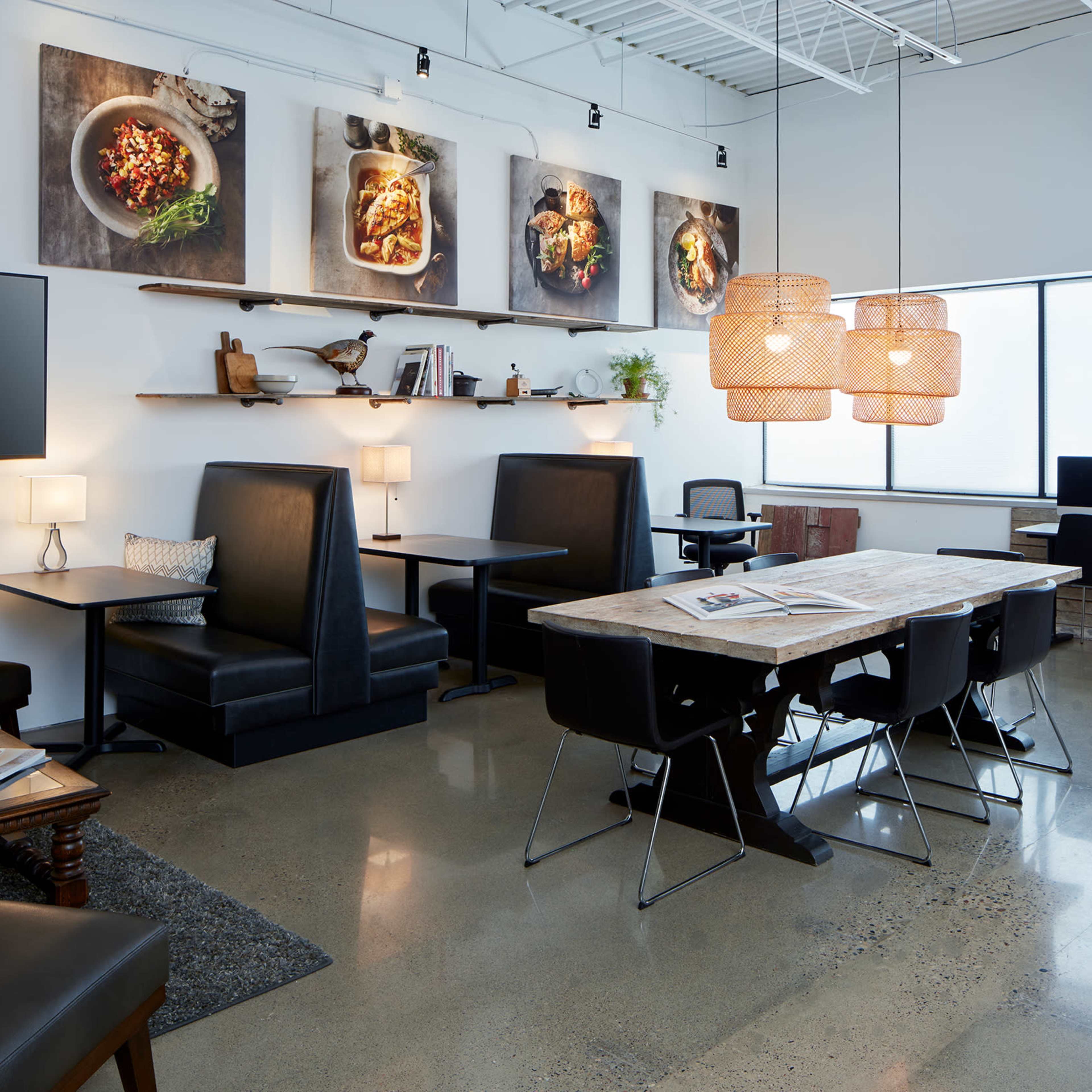 A modern office space with various seating areas, a large wooden table, and wall-mounted artworks.