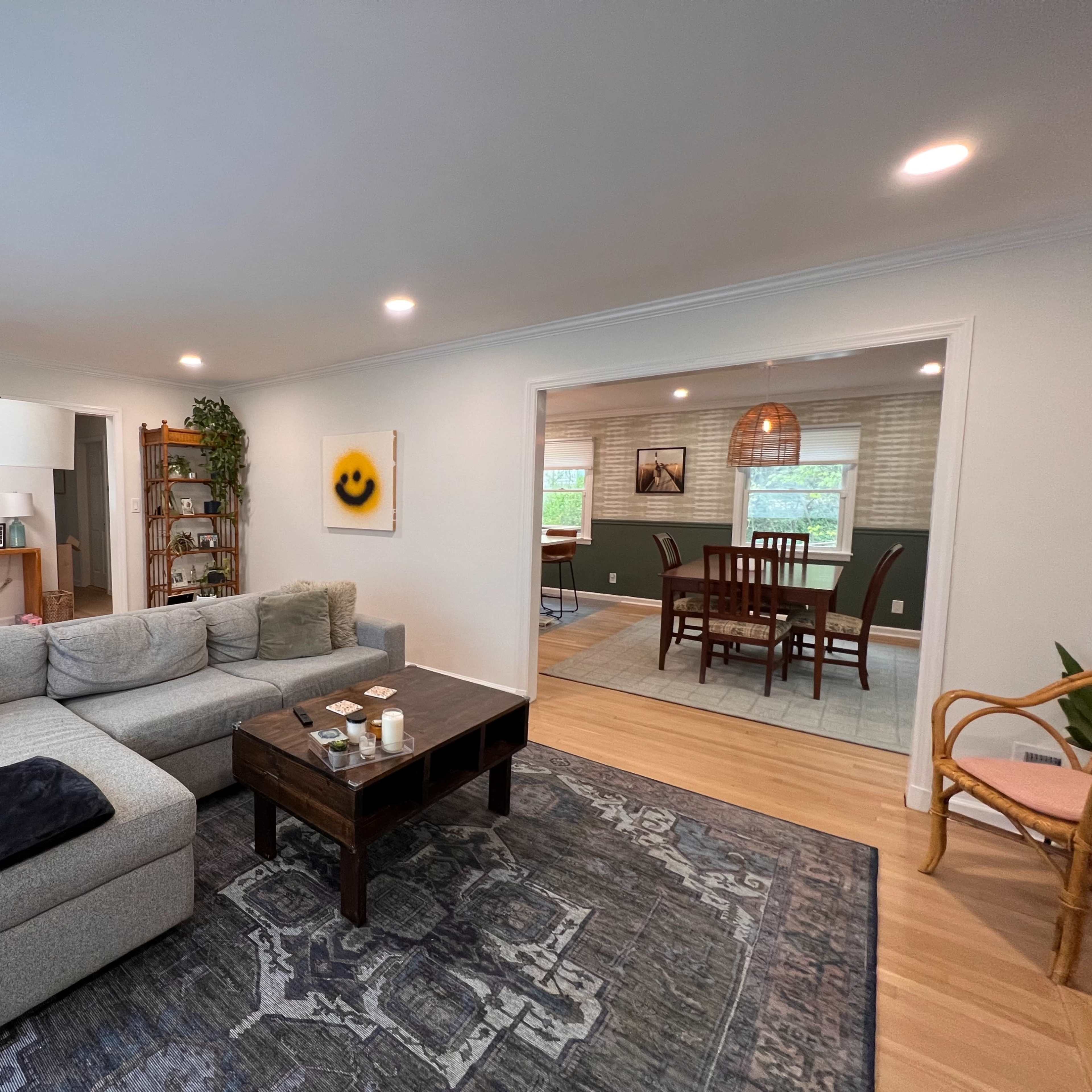 A cozy living room with a gray sectional sofa, a coffee table in front, and an adjacent dining area visible through an open doorway.
