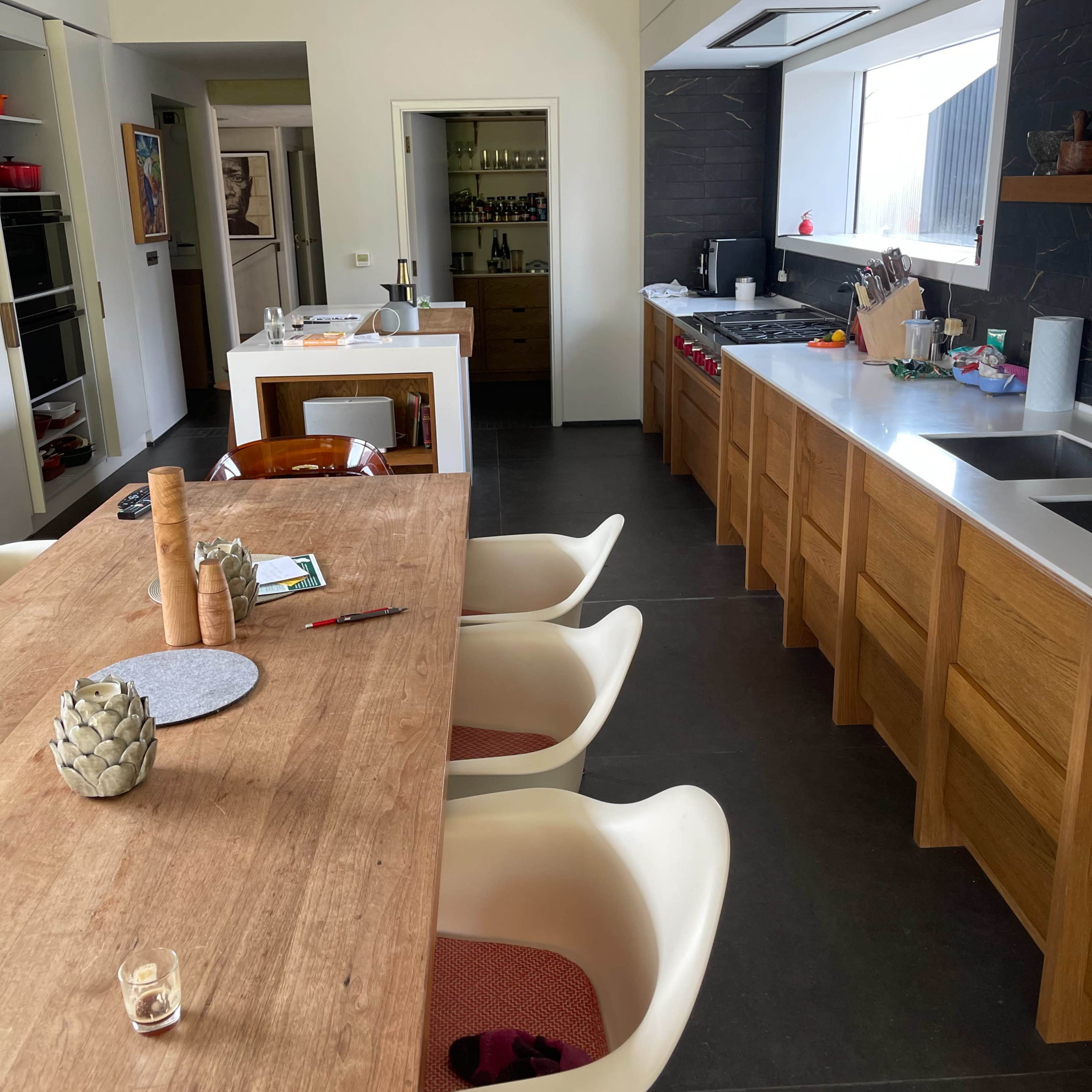 A modern kitchen and dining area featuring a wooden table with chairs, a sleek countertop, and organized cabinetry.