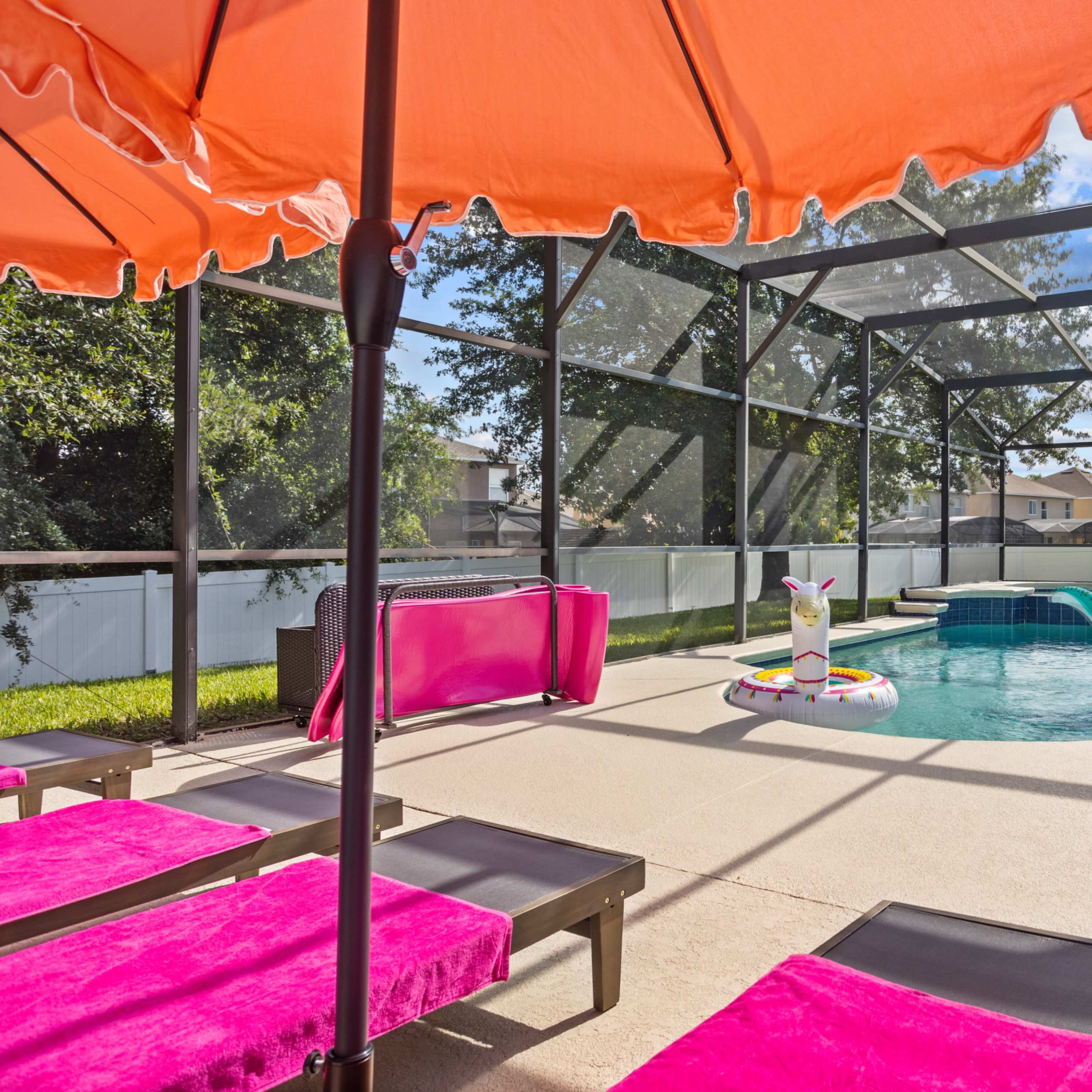 A backyard pool area with lounge chairs, an orange umbrella, and inflatable toys floating in the water.