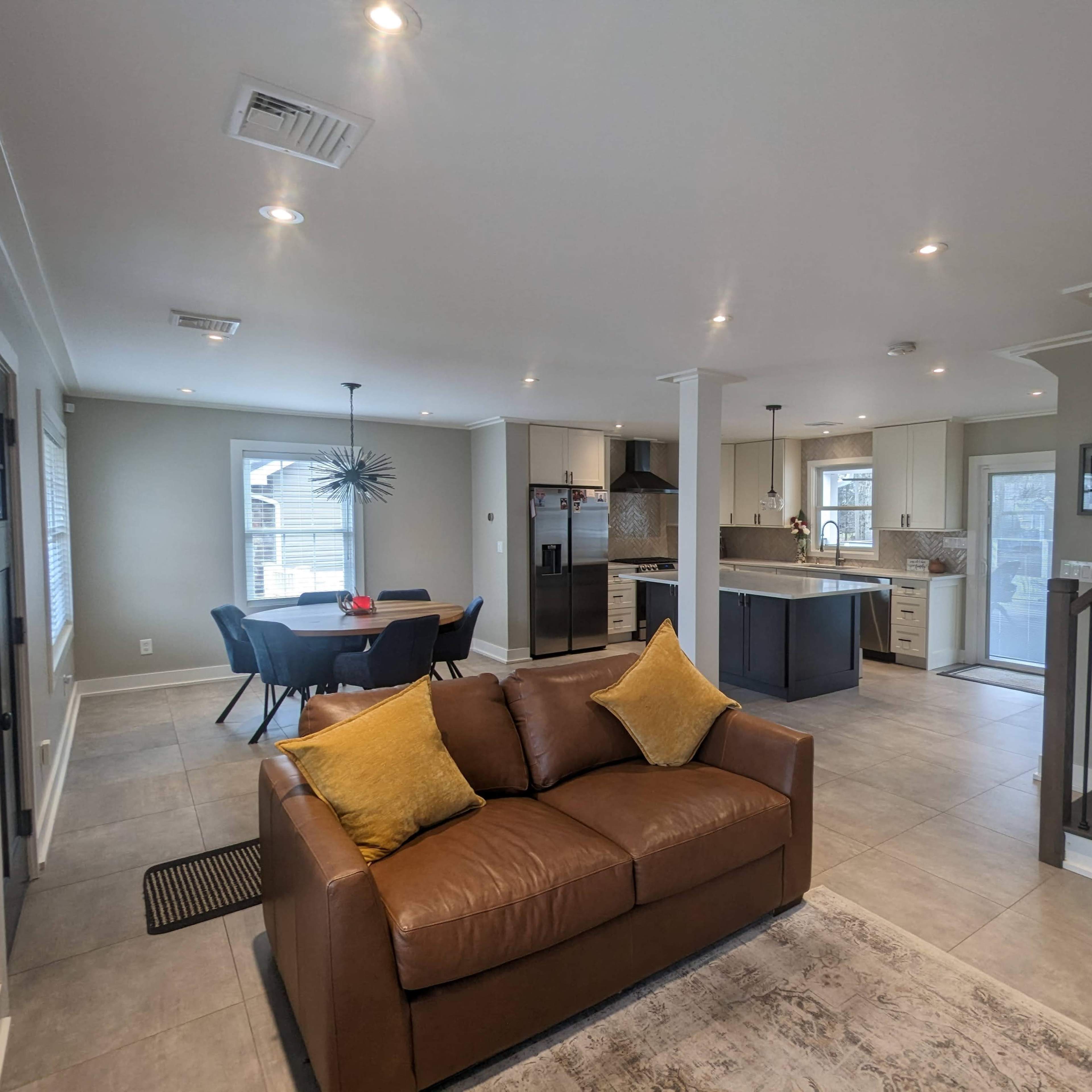 An open-concept living area with a brown couch, a dining table, and a kitchen in a modern home.