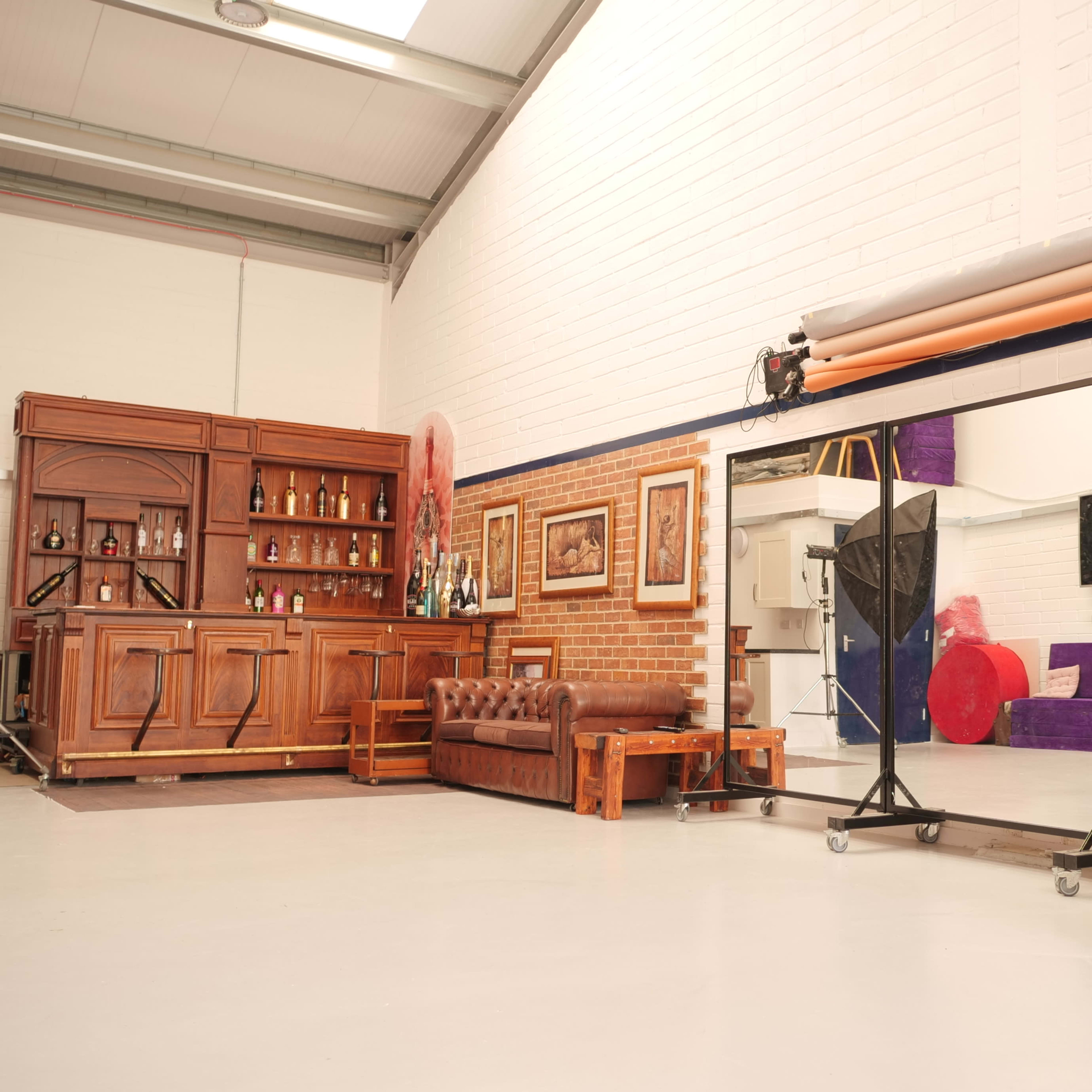An industrial-style interior with a wooden bar, a leather couch, and colorful backdrops on the wall.