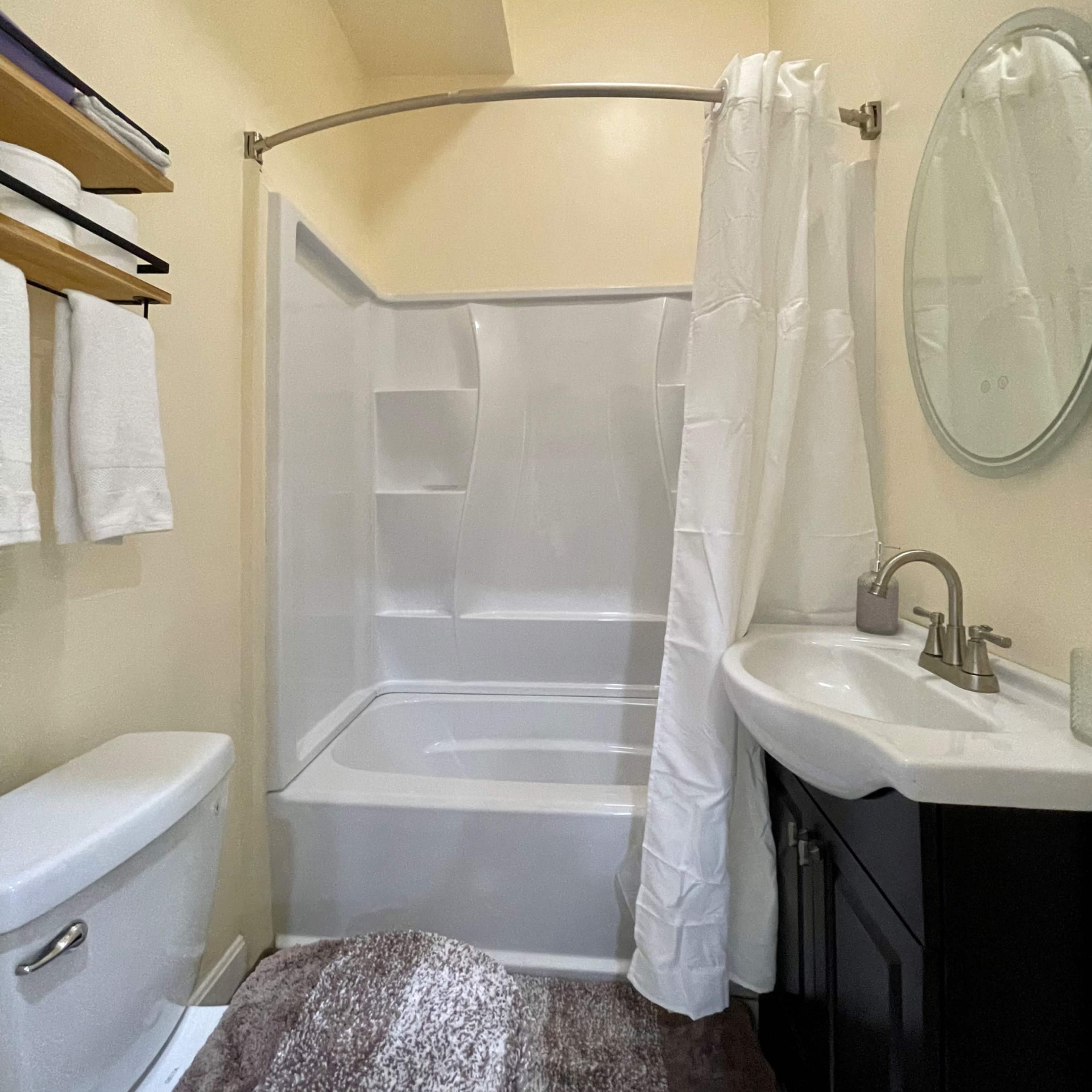 A bathroom with a toilet, sink, and a shower enclosed by a curtain.