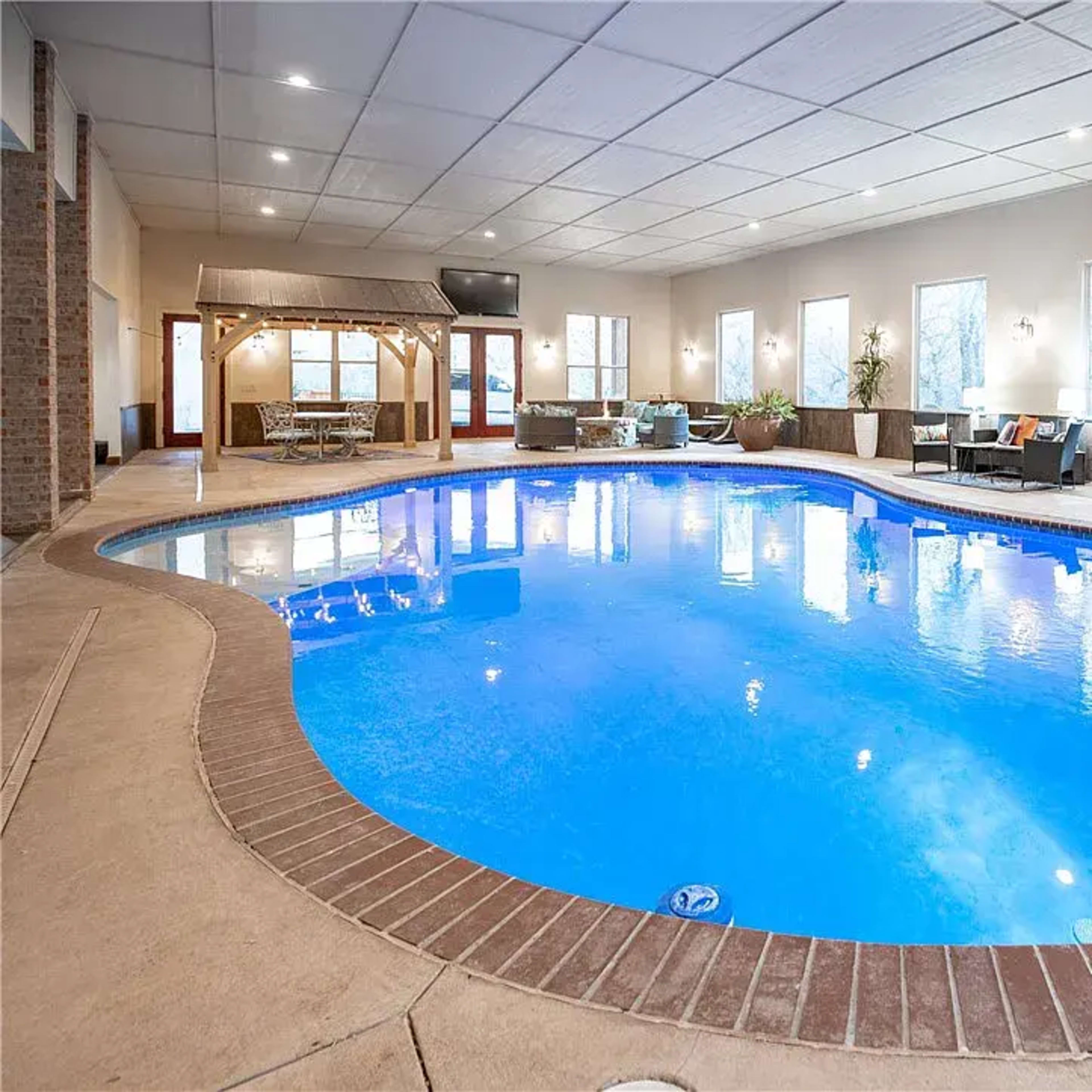 An indoor swimming pool surrounded by a seating area and large windows allowing natural light.