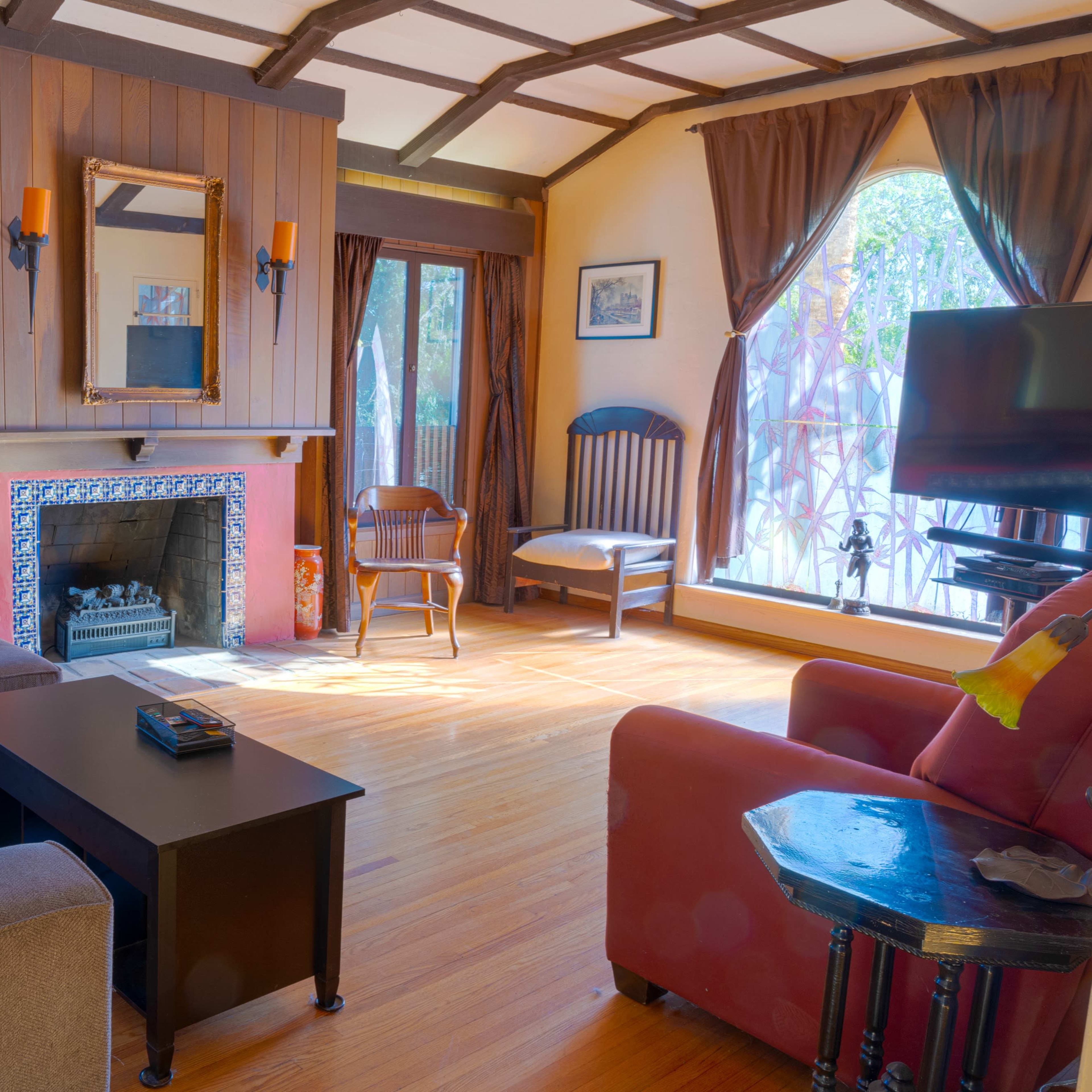 A cozy living room featuring a fireplace, a large sofa, a coffee table, and large windows with curtains.