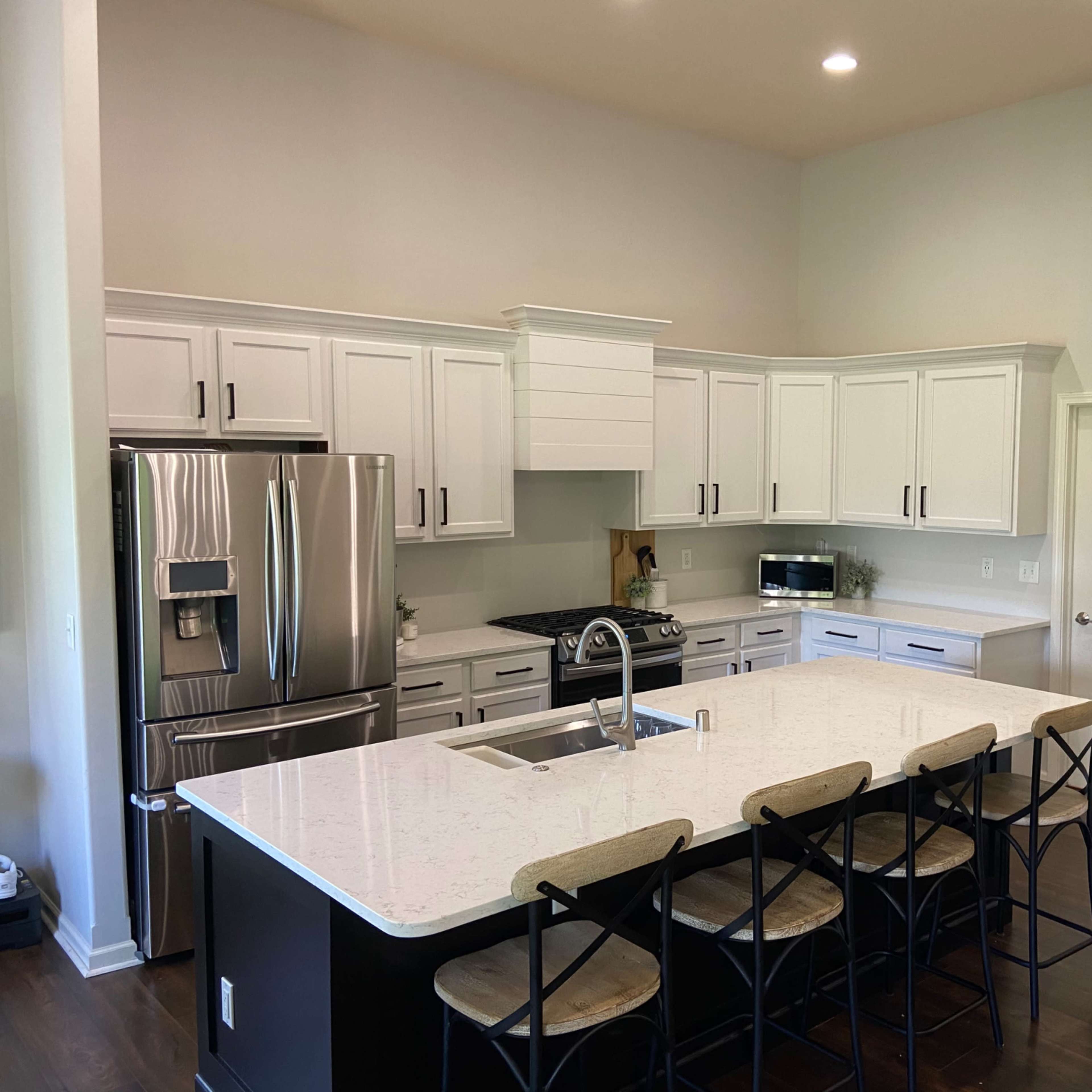 A modern kitchen features white cabinetry, black countertops, and a large island with bar seating.