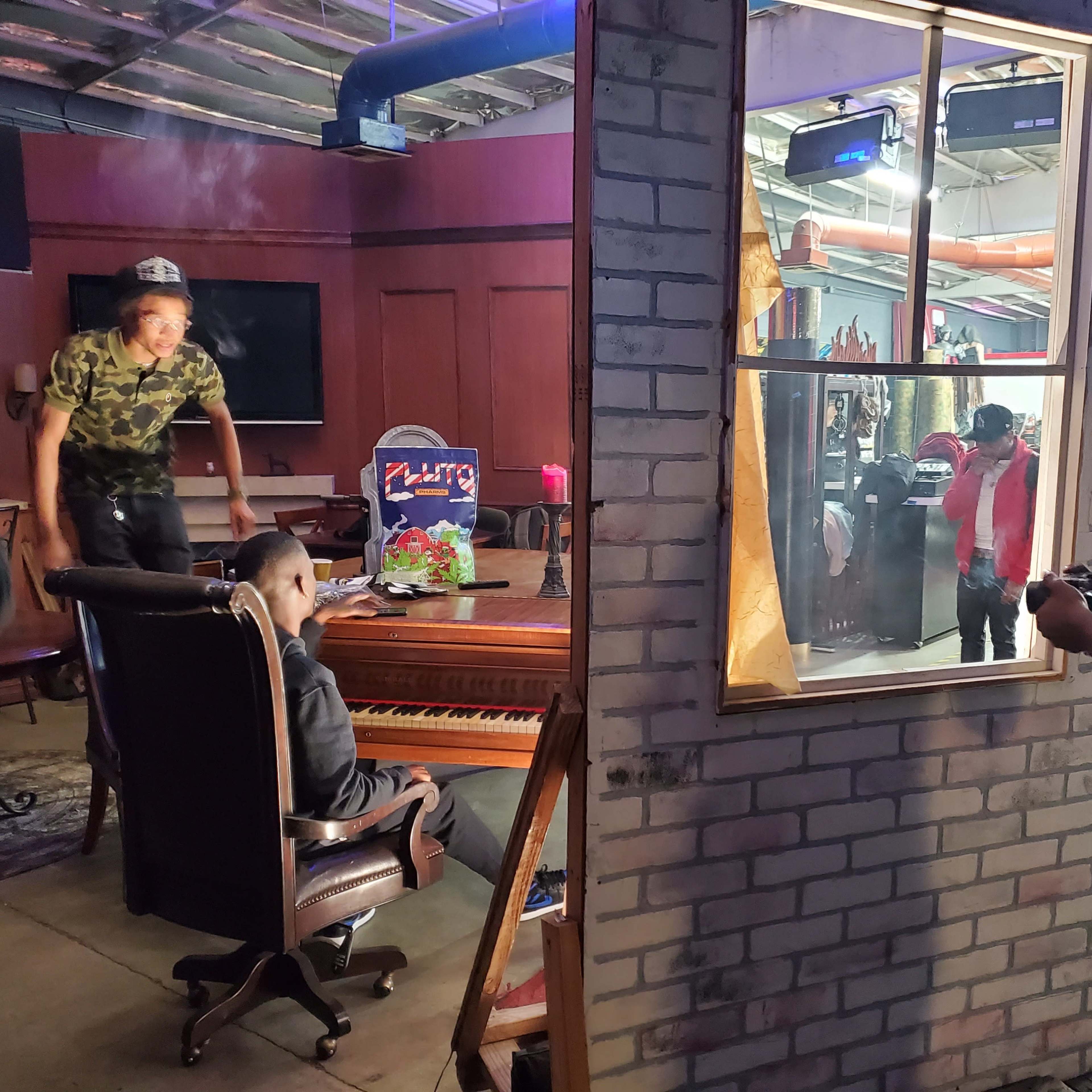 A small set depicts a musician playing a piano while others interact in a room designed to resemble a living space.