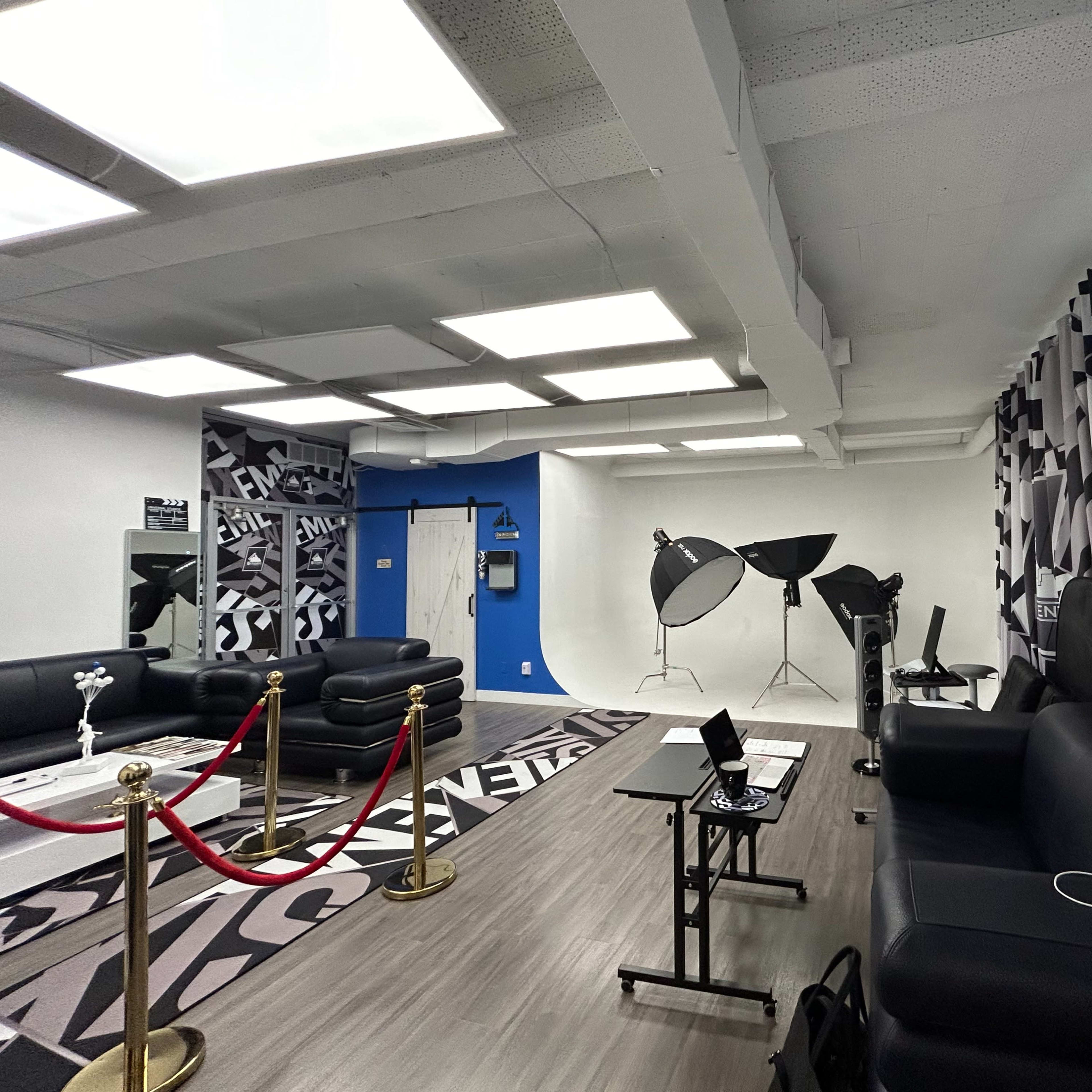 The room features black leather furniture, modern lighting fixtures, and photography equipment, with a stylish rug on the floor.