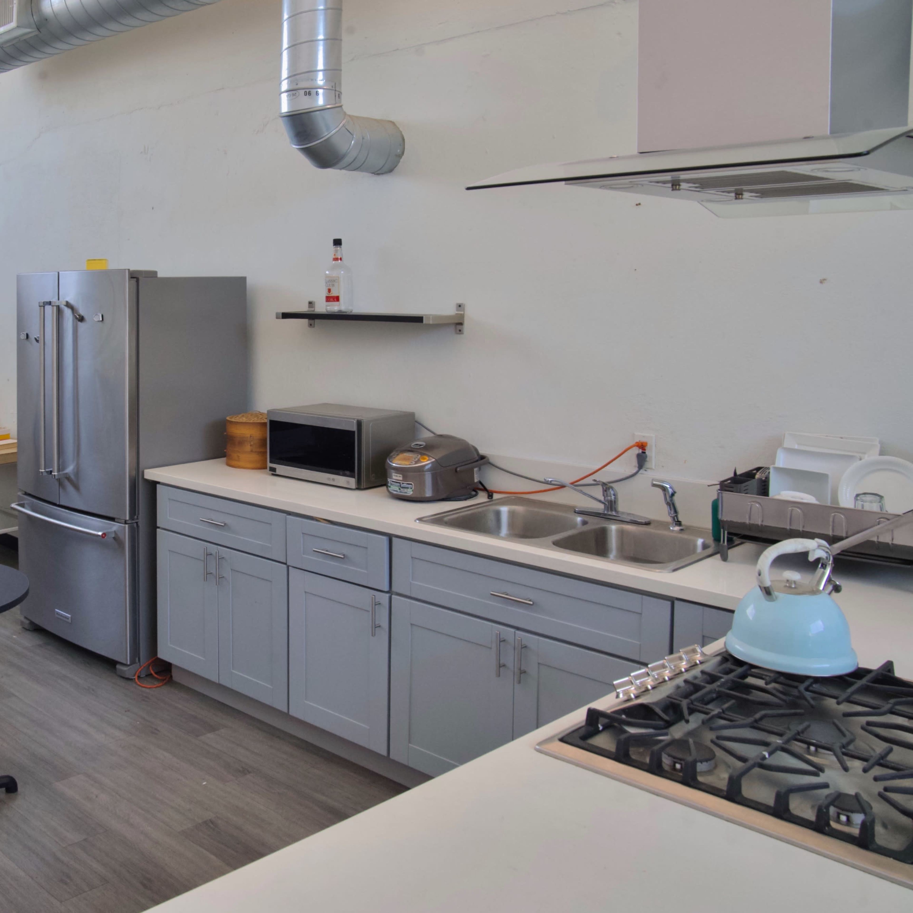 A minimalist kitchen and living area with a refrigerator, stove, and seating arrangement.