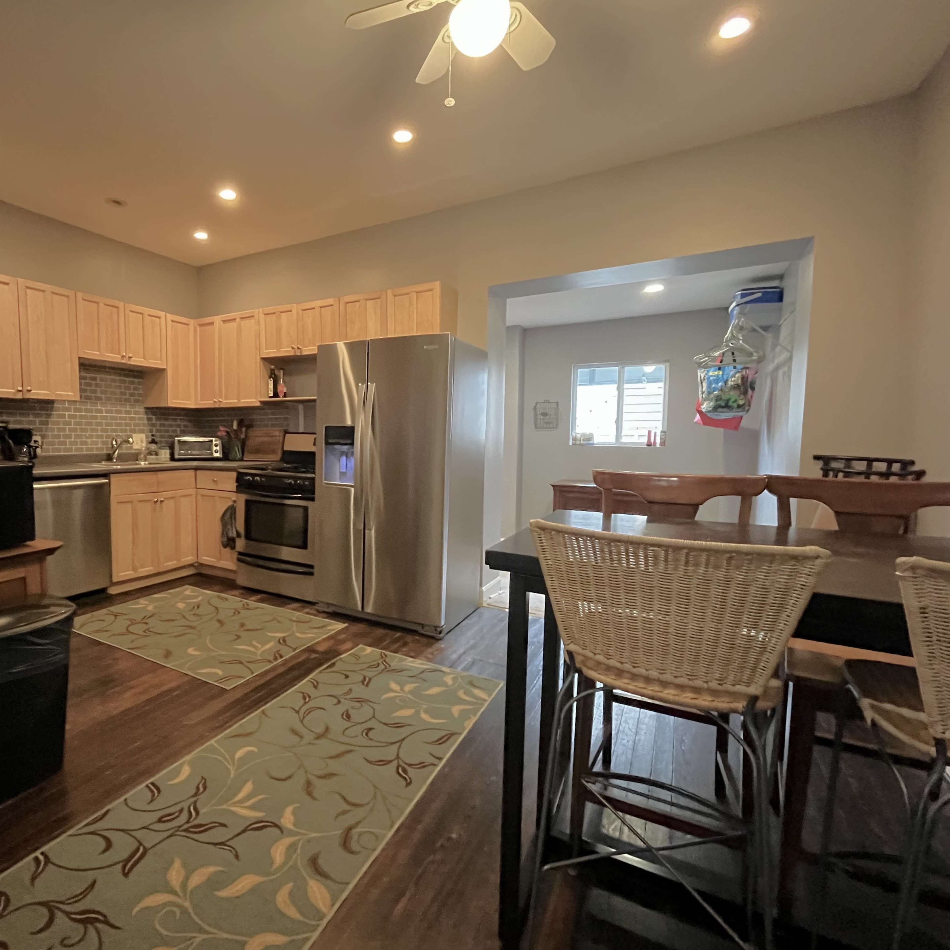 A modern kitchen with wooden cabinets, stainless steel appliances, and a dining table next to the countertops.