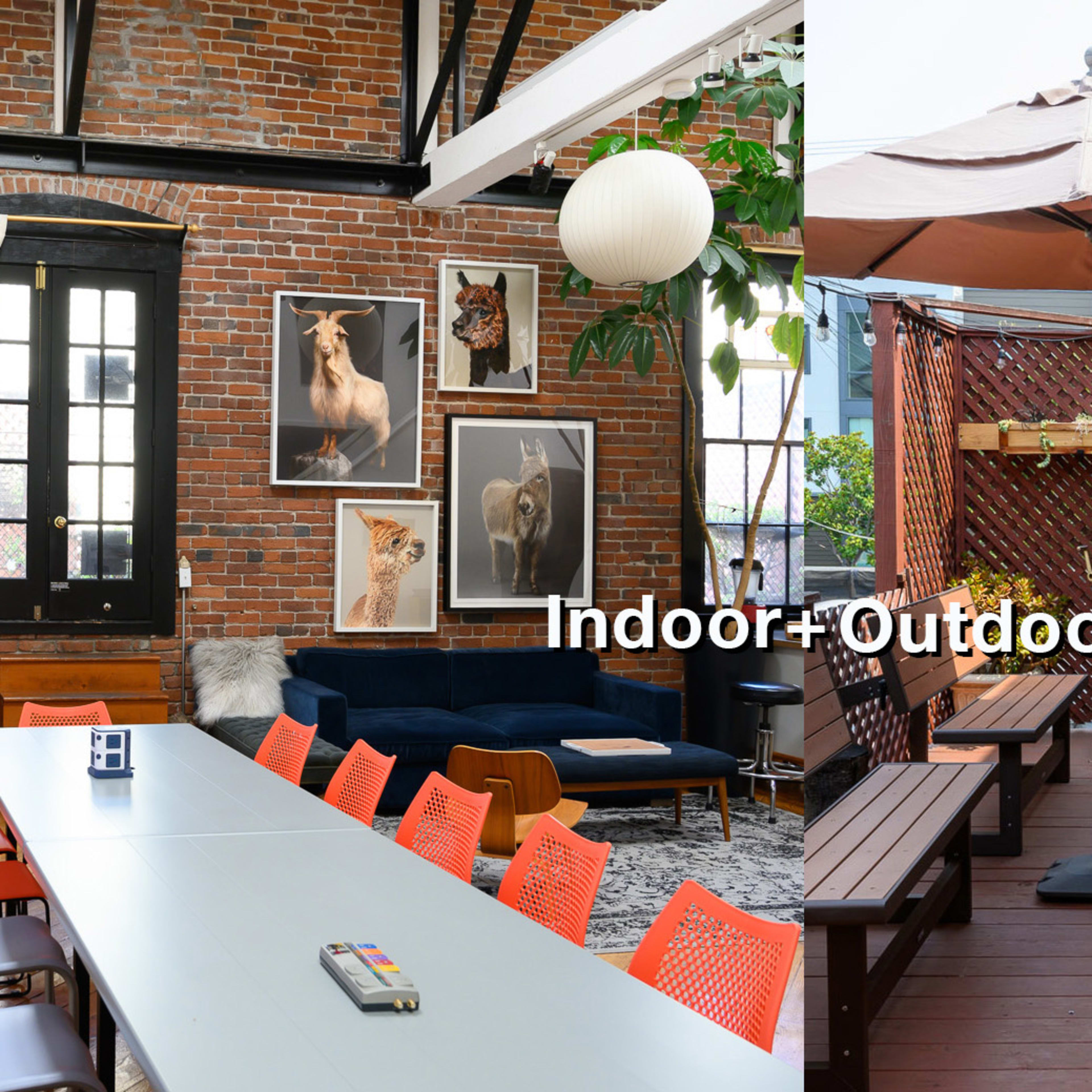 A large room with a long table and colorful chairs on one side, and an outdoor patio area with wooden seating and a fire pit on the other.