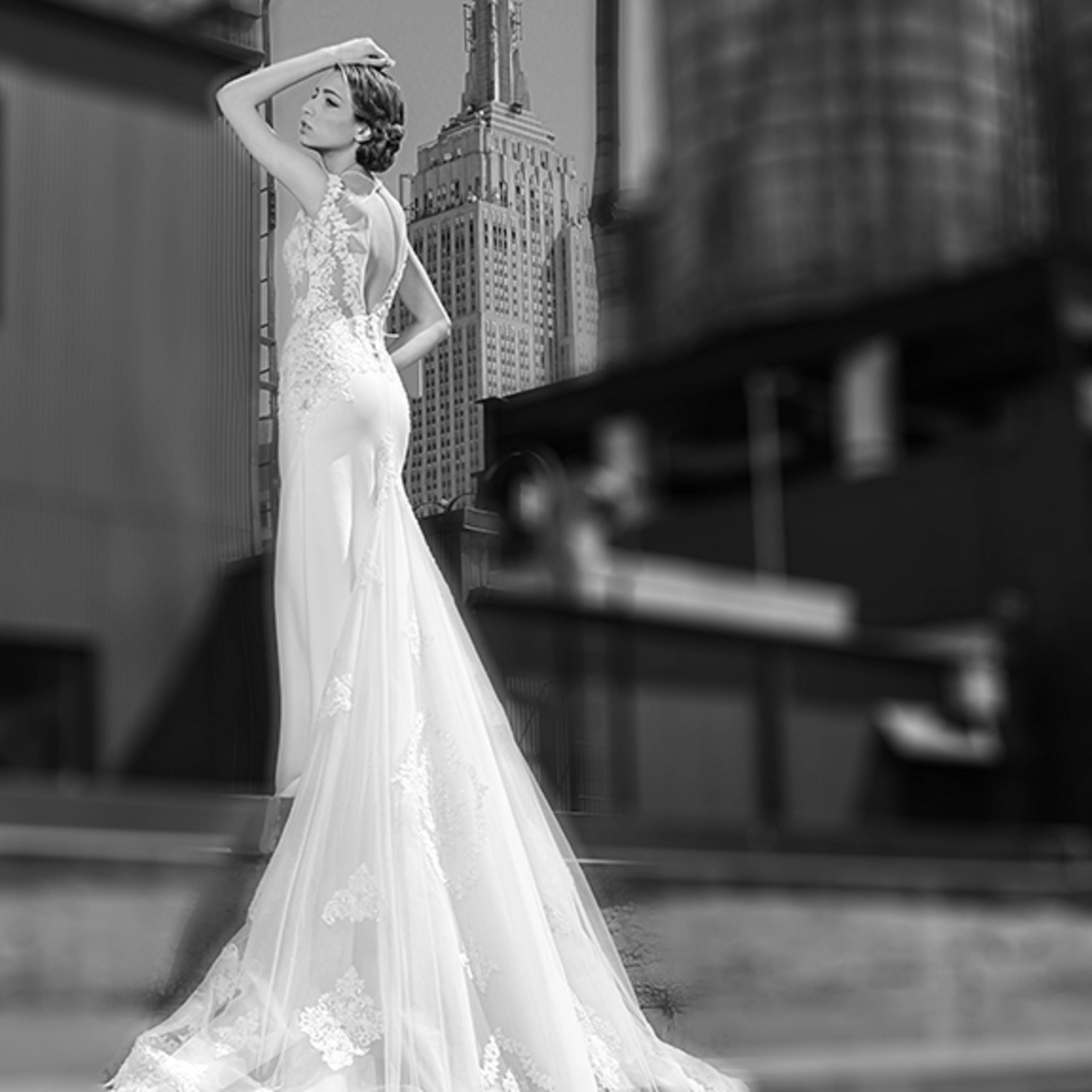 A woman in a white bridal gown poses with the Empire State Building in the background.