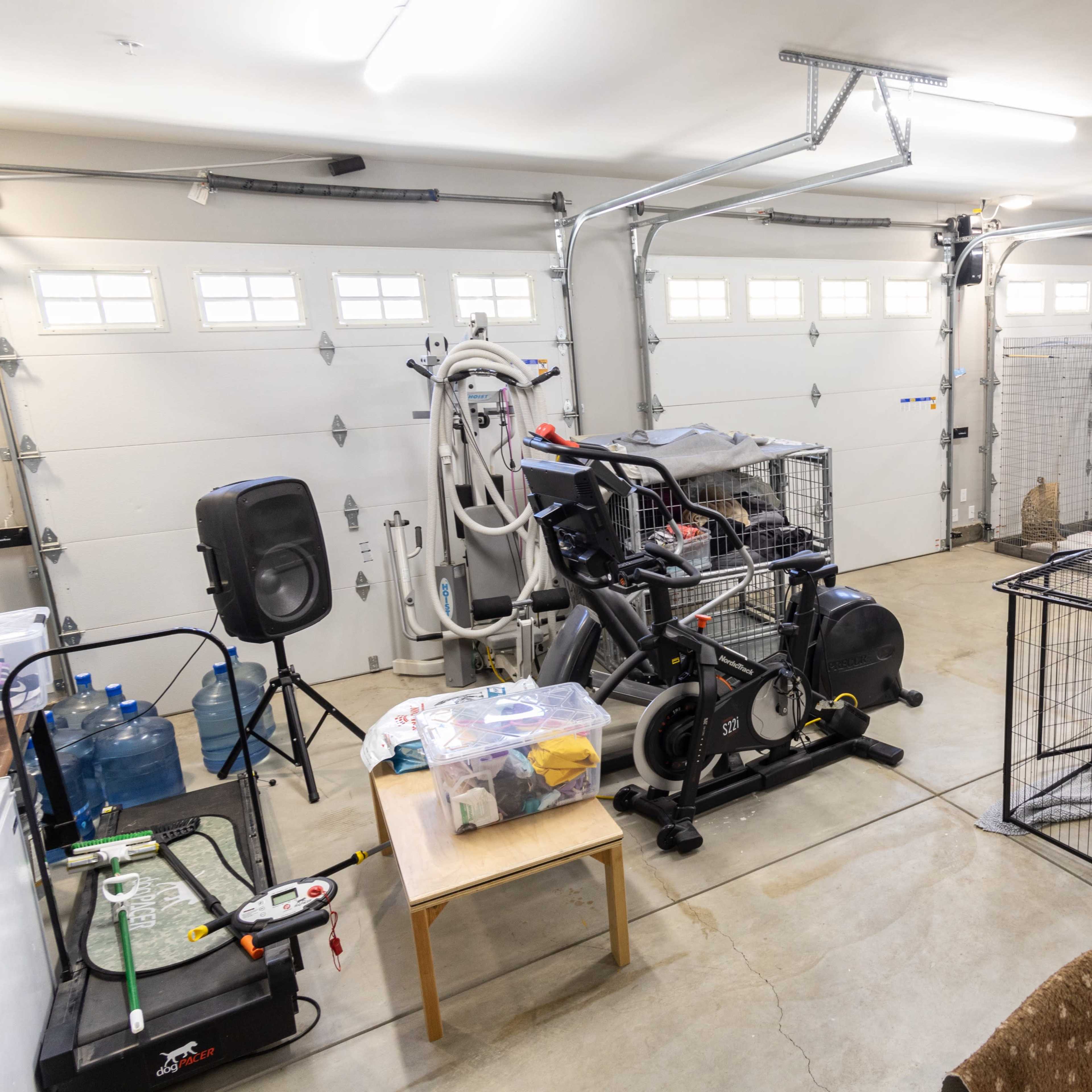 A garage with exercise equipment, storage items, and multiple animal enclosures arranged around the space.