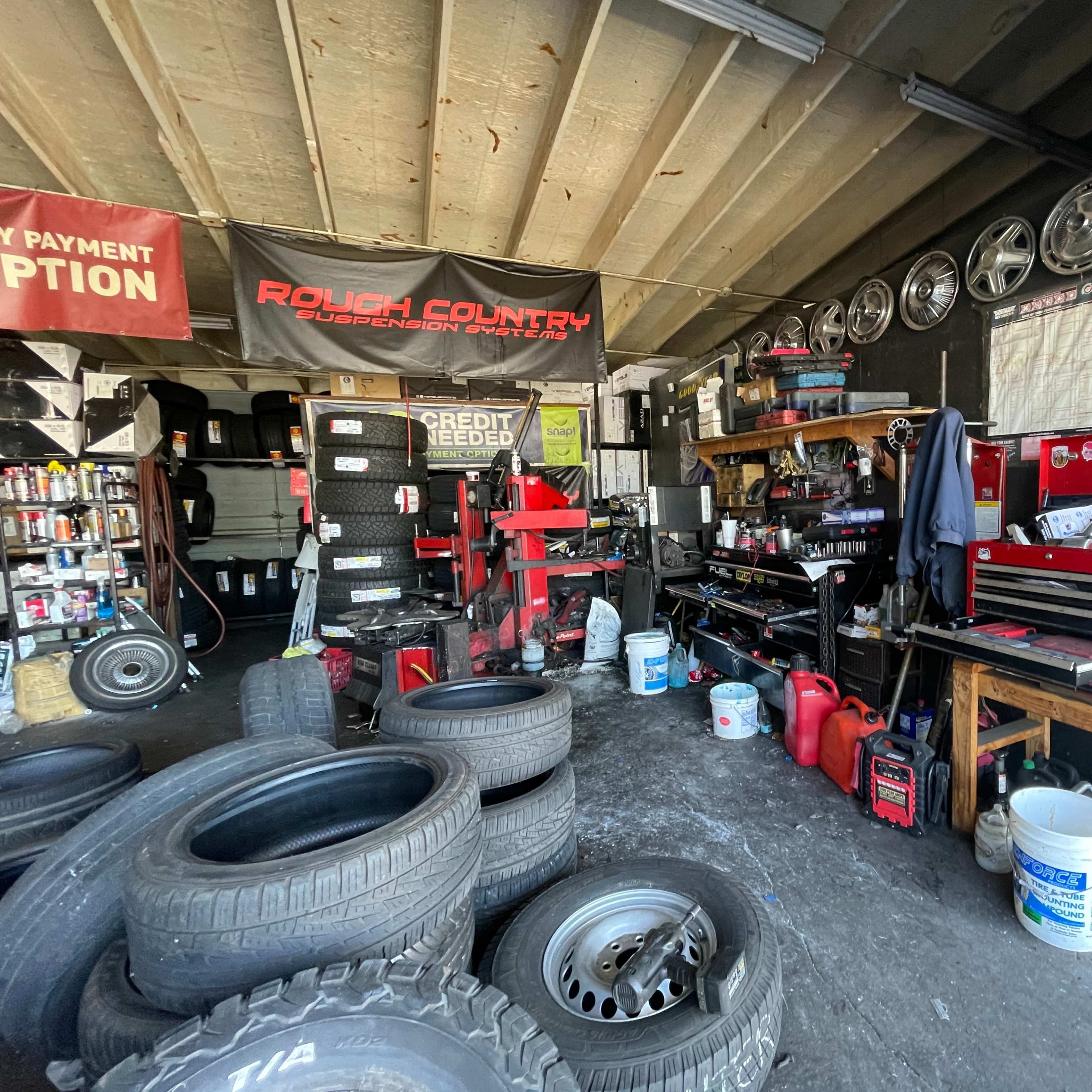 An automotive shop interior with tool storage, tire stacks, and a tire-changing machine.
