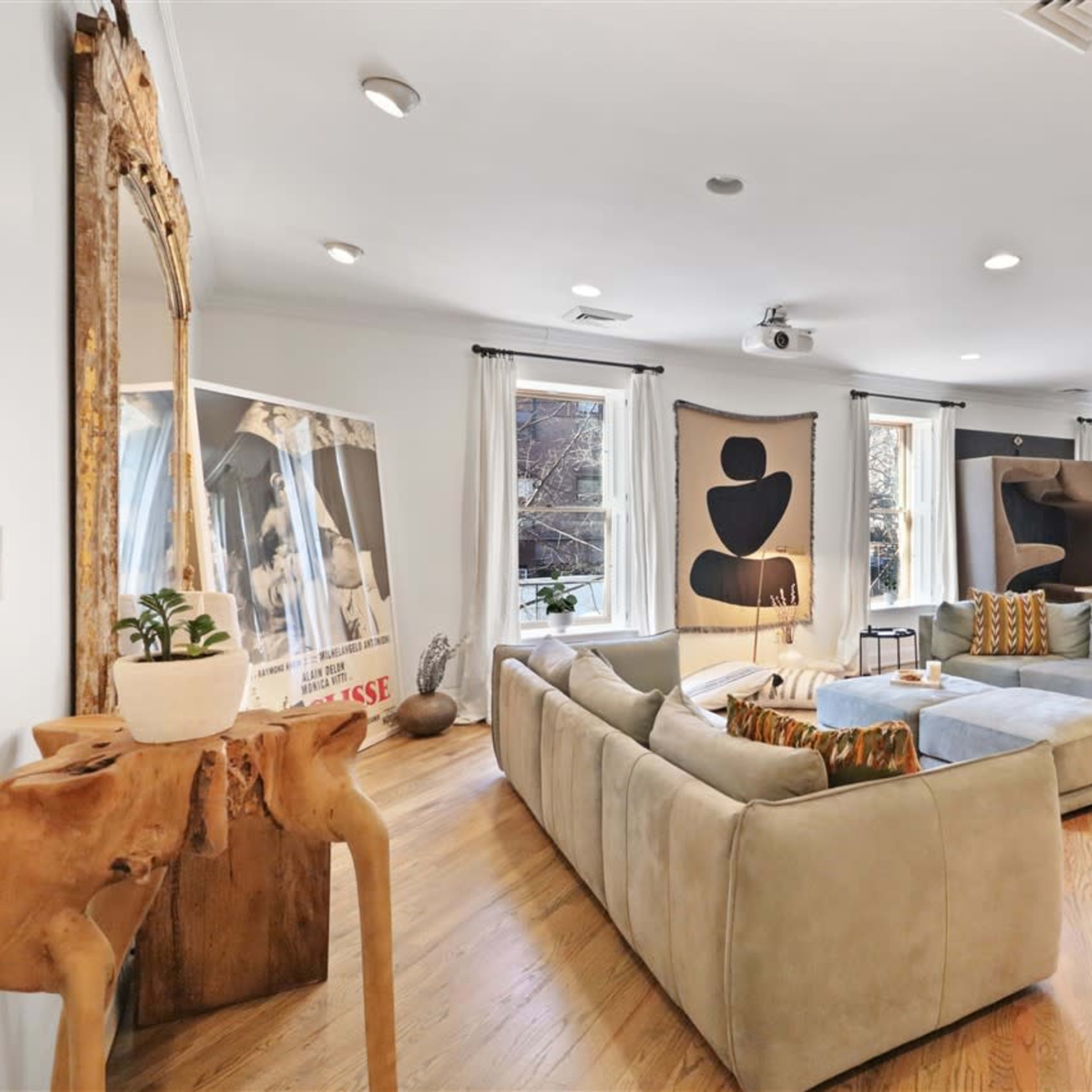 A spacious living room featuring a large sectional sofa, modern artwork on the walls, and a dining area in the background.