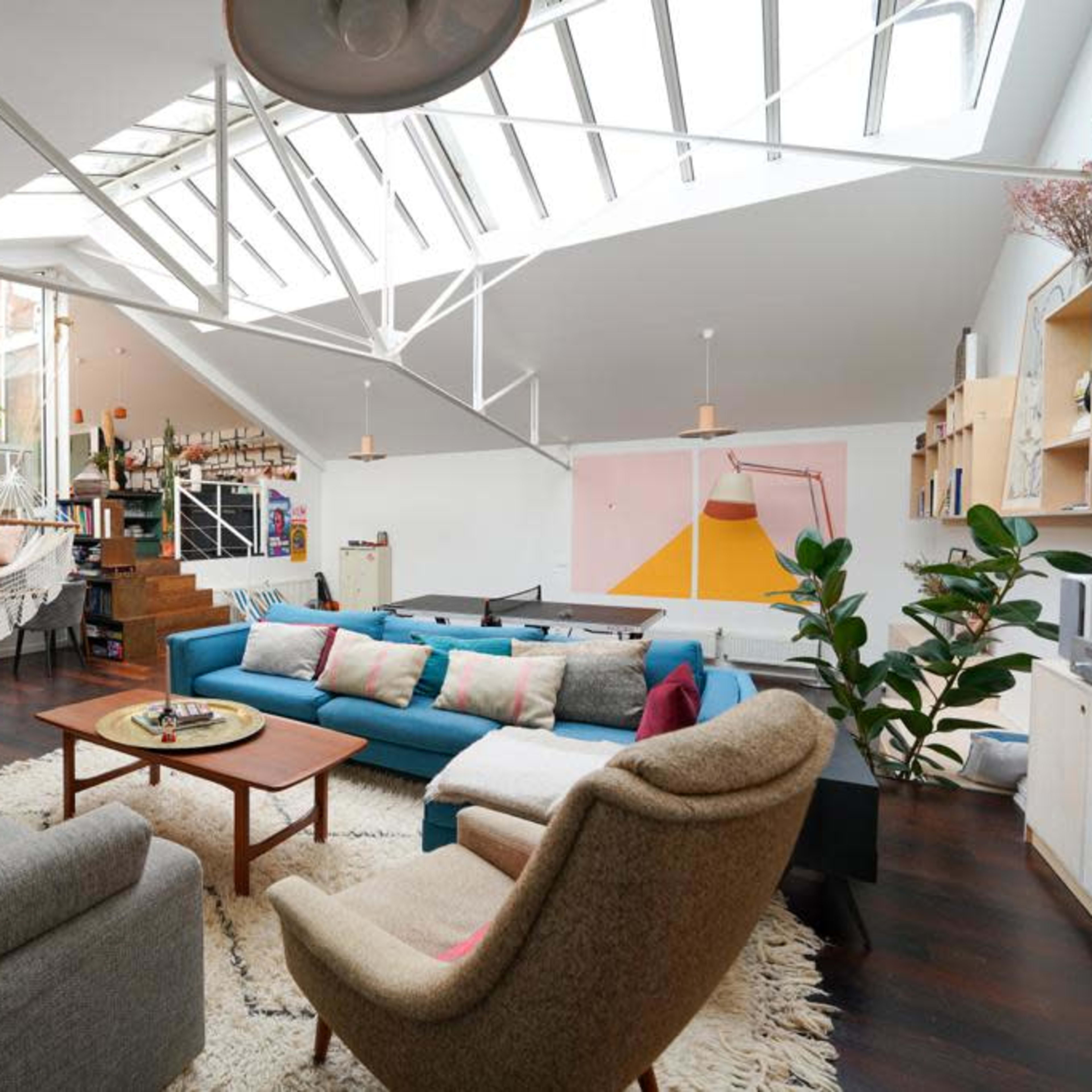 A spacious, modern living area with a mix of seating arrangement, large windows, and decorative plants.