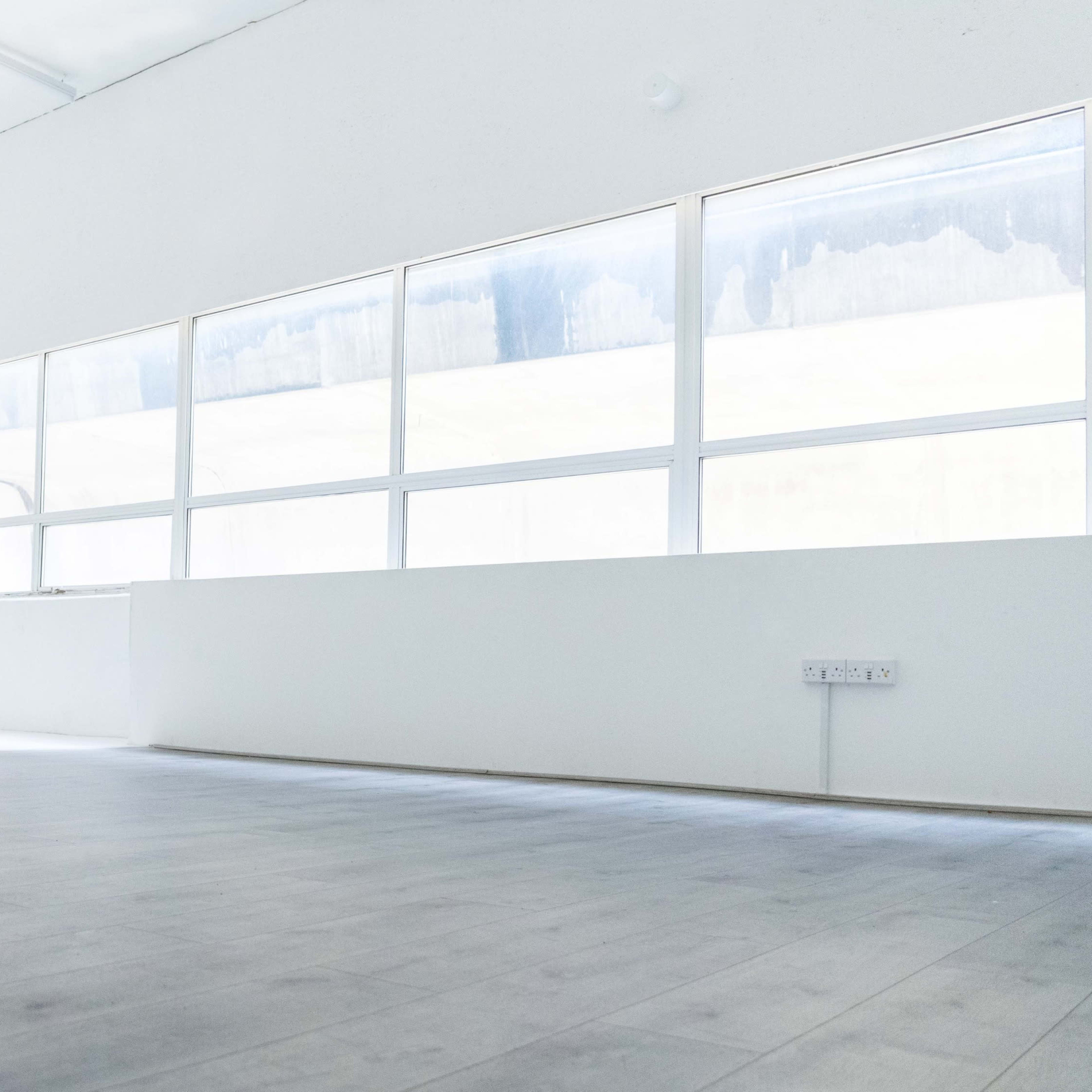 A spacious, empty room with large windows allowing natural light to enter.