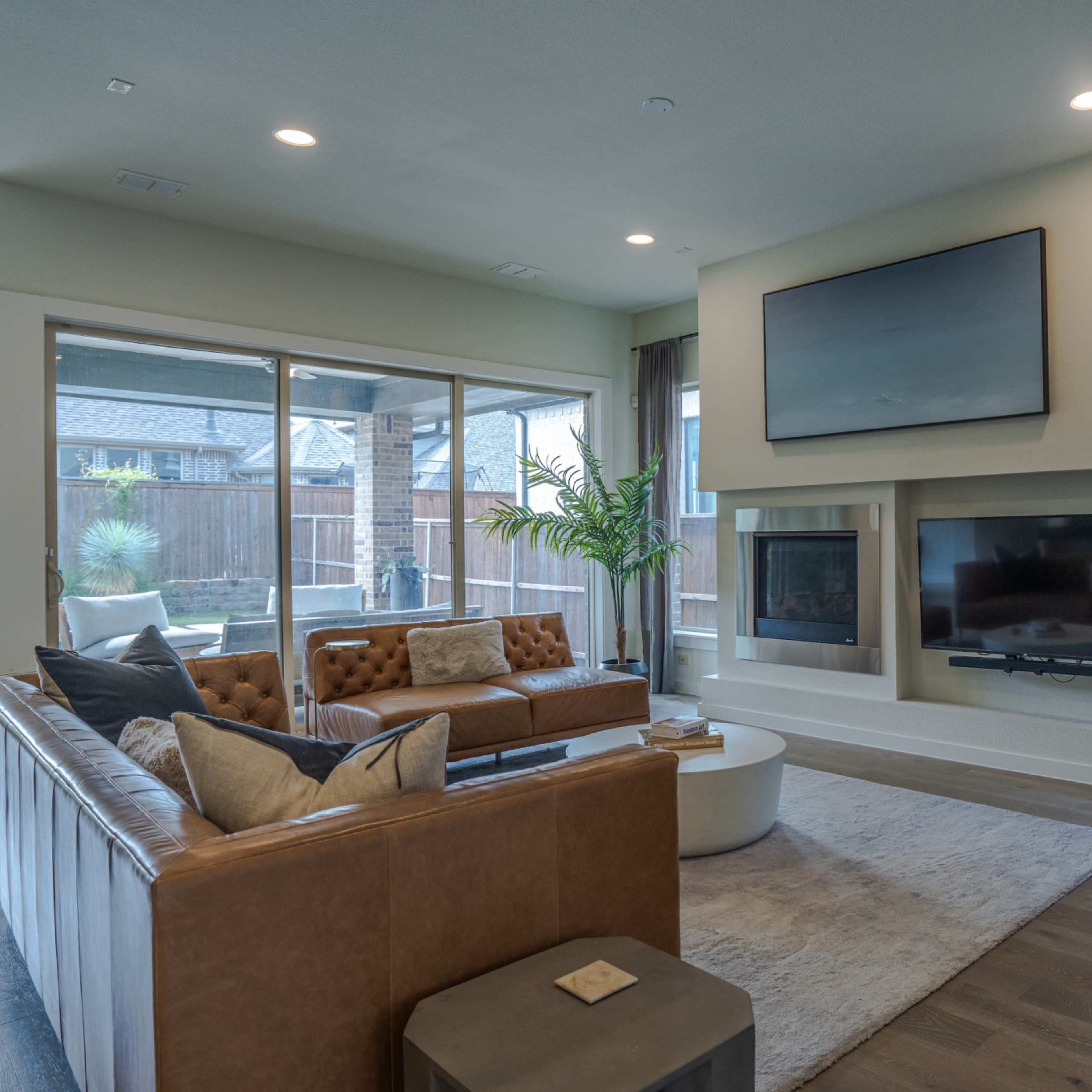 A modern living room with a leather couch, a coffee table, and a wall-mounted television above a fireplace.