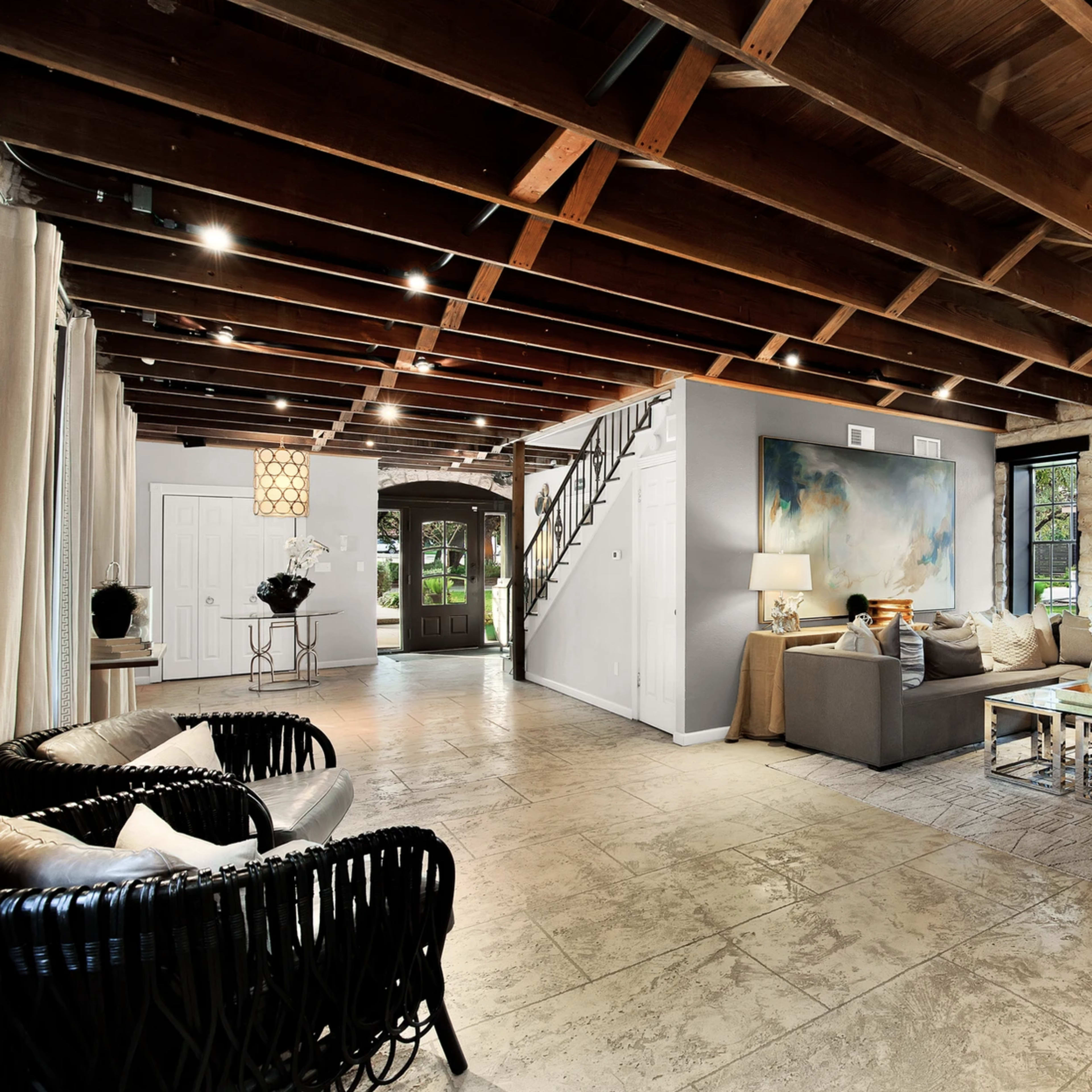 A spacious living room with wood-beamed ceilings, stone walls, and a mix of modern and classic furnishings.